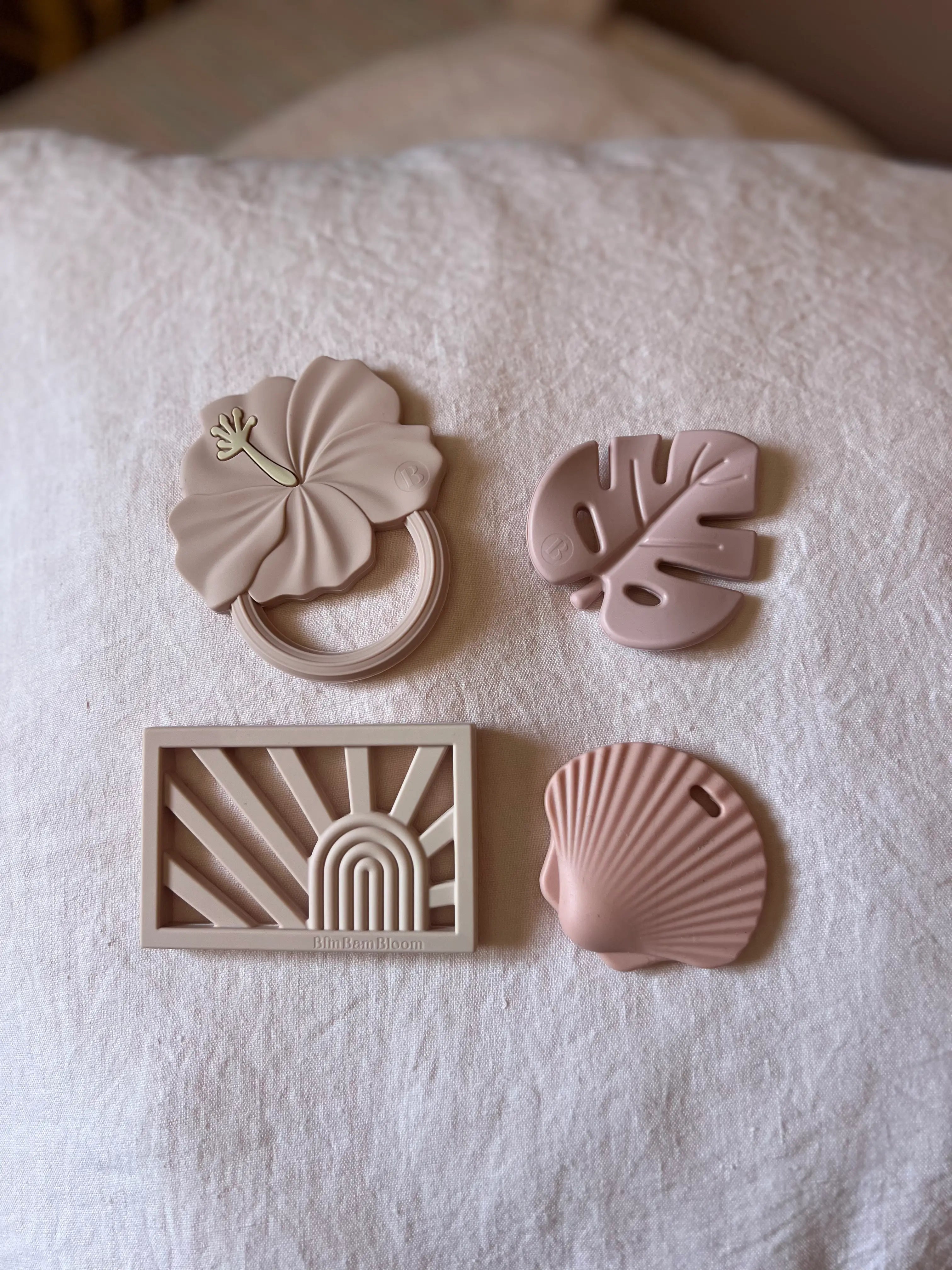 Quatre anneaux de dentition rose par Bim Bam Bloom sur fond pastel.