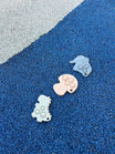Anneau de dentition Pop-It de Bim Bam Bloom sur un fond vibrant, offrant un design ludique et coloré pour soulager les gencives de bébé. Un elephant bleu, un champignon beige et un dinosaure vert.