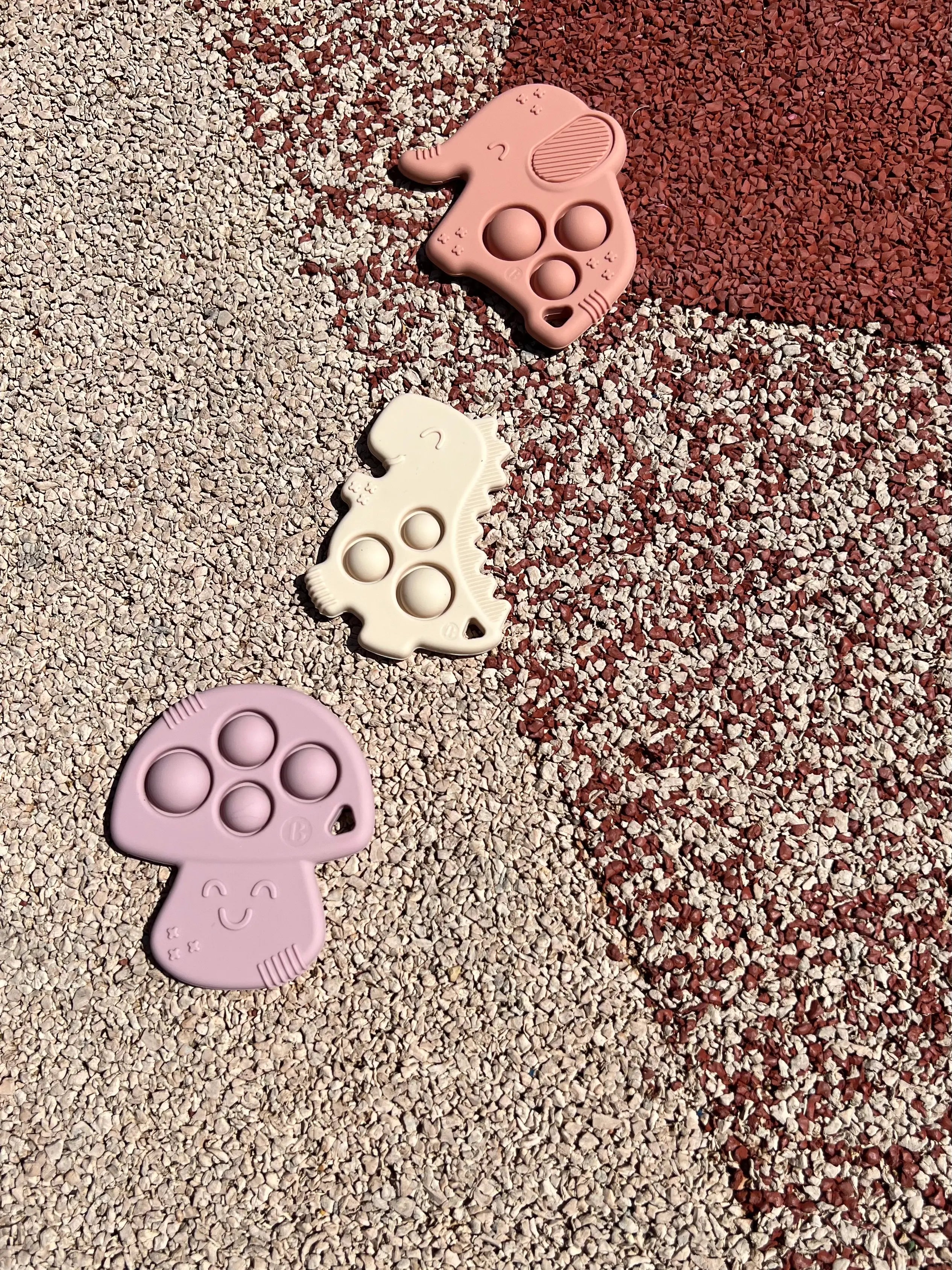 Anneau de dentition Pop-It de Bim Bam Bloom sur un fond coloré, offrant un design ludique pour soulager les gencives de bébé.