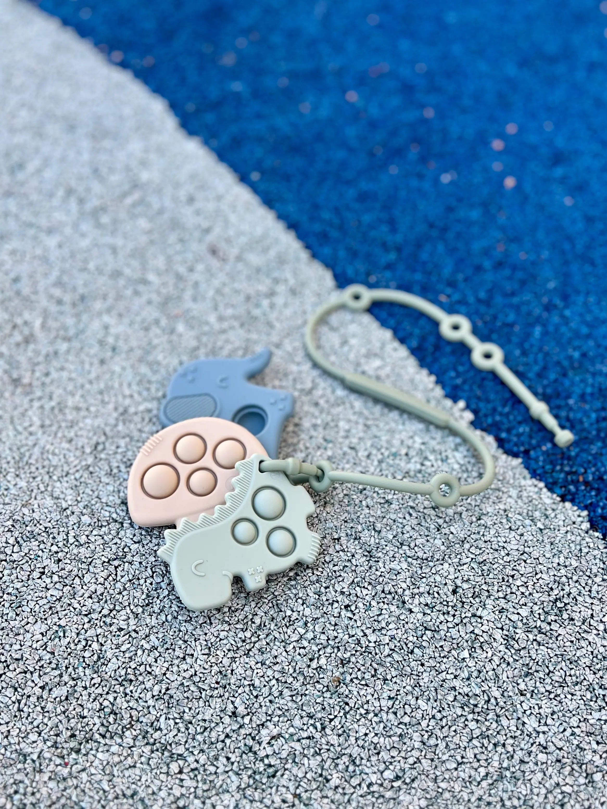 Anneaux de dentition Pop-It attachés à un Lovie Link® de Bim Bam Bloom, permettant à bébé de mâcher en toute sécurité lors de ses aventures.