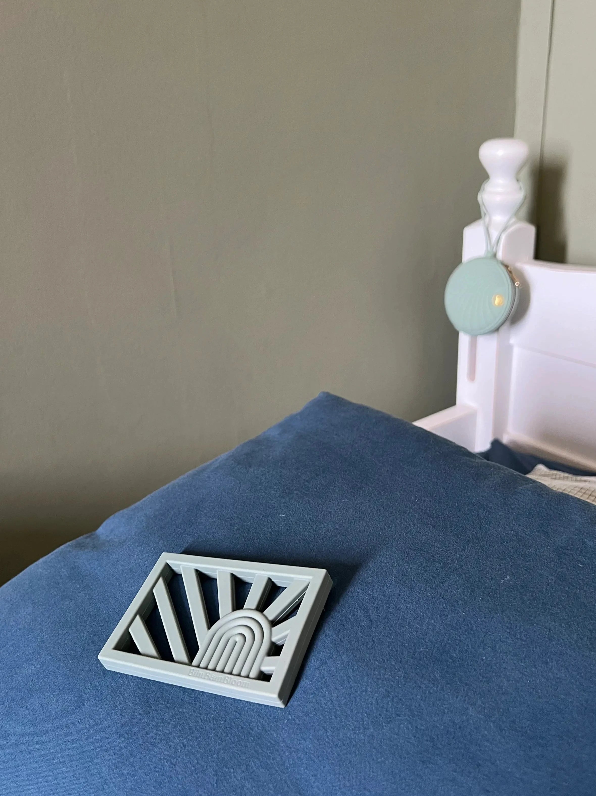 Anneau de dentition Rainbow en couleur vert sur un lit d'enfant, un jouet de dentition au design arc-en-ciel sûr et sain pour apaiser les gencives de bébé.