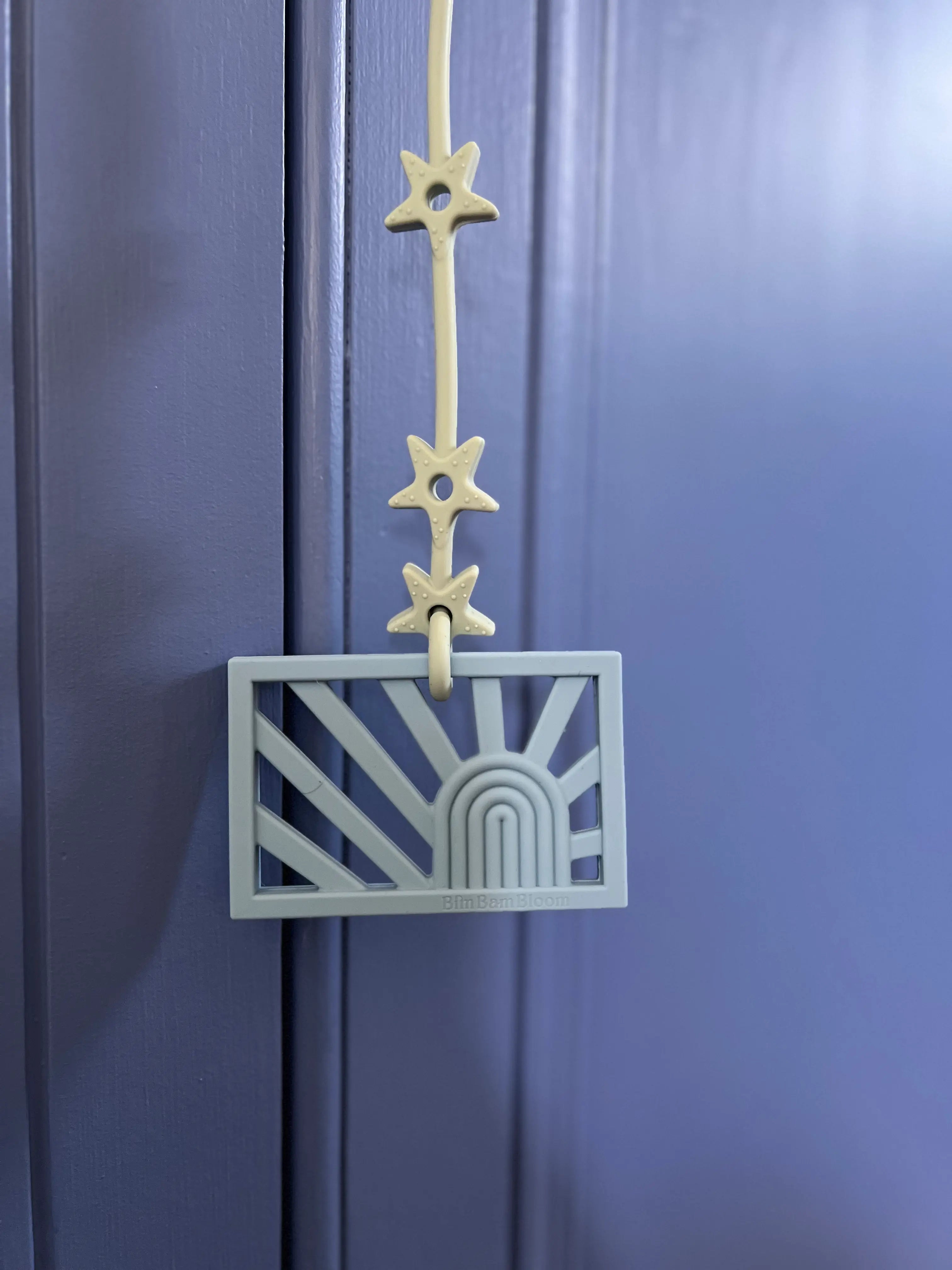 Anneau de dentition Rainbow attaché à un attache-doudou Lovie Link® pour mâchouiller en toute tranquillité, garantissant que le jouet reste toujours à portée de main, par Bim Bam Bloom