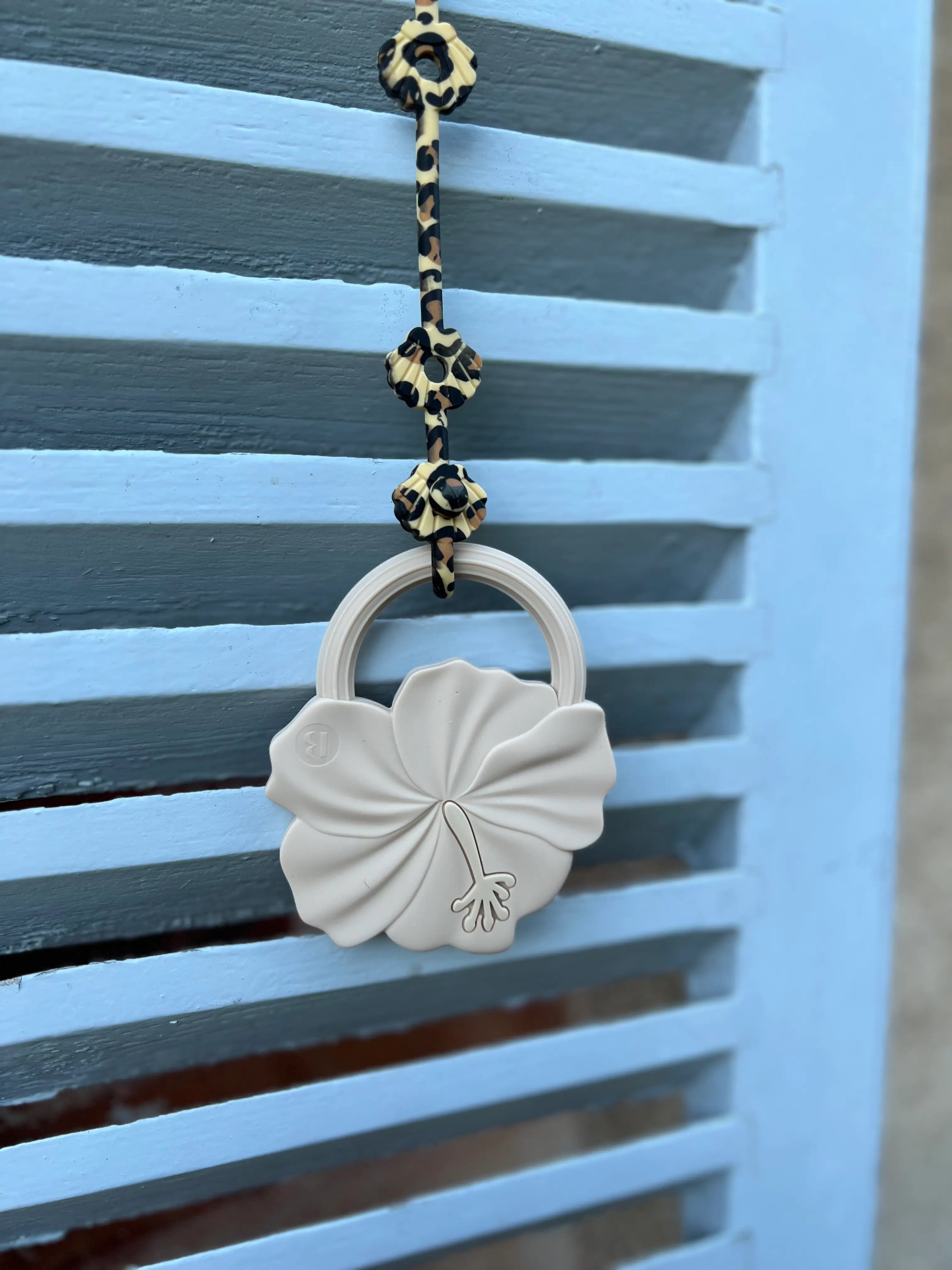 Anneau de dentition Flower Power en Beige Matin Paisible attaché avec un attache doudou pour poussette Lovie Link Shell Leopard, un jouet de dentition doux et sûr pour le confort de votre bébé.