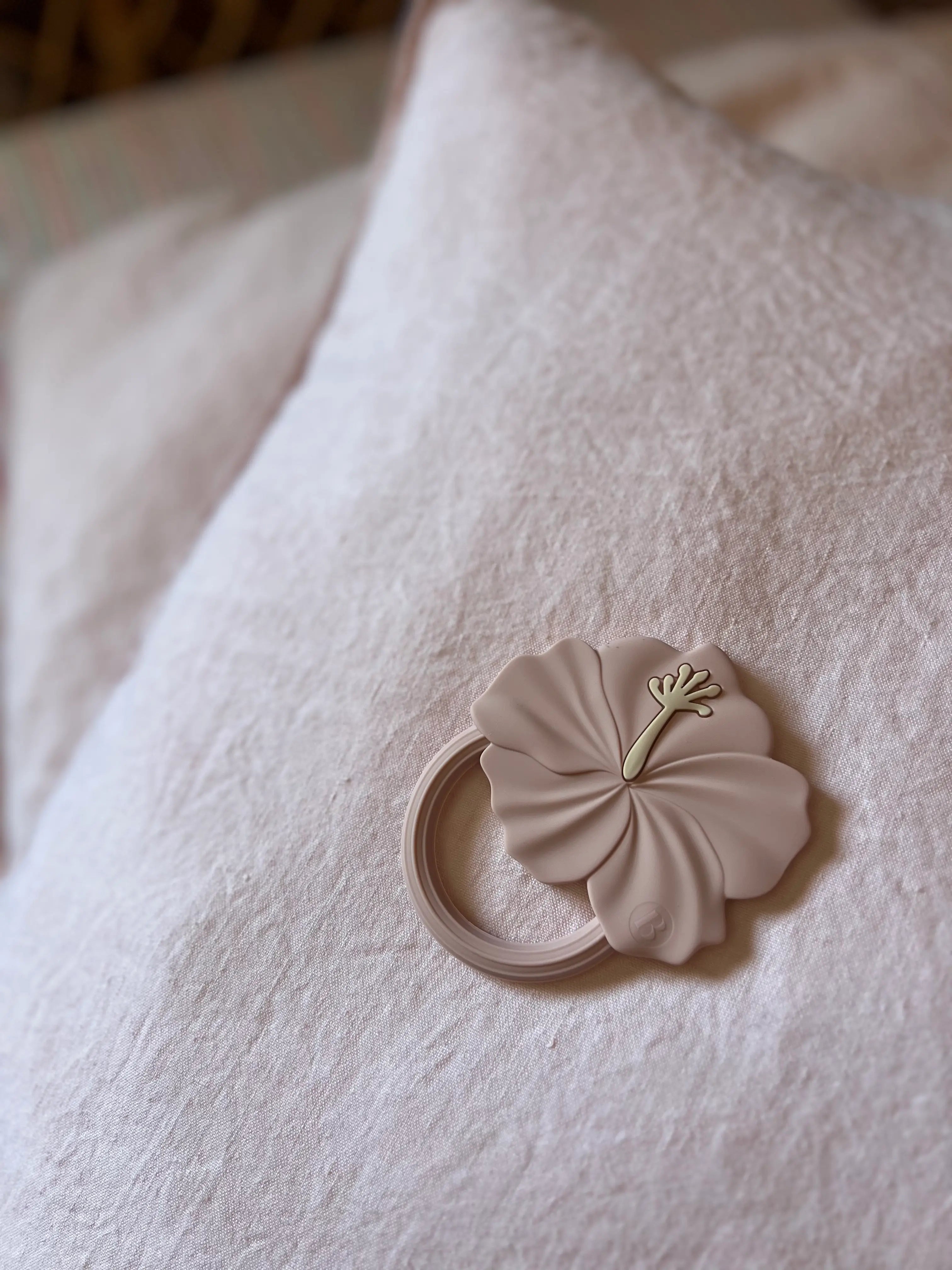 Anneau de dentition Flower Power en Rose sur fond pastel, fabriqué en silicone 100% alimentaire ce jouet de dentition apaisera les gencives douloureuses de bébé.