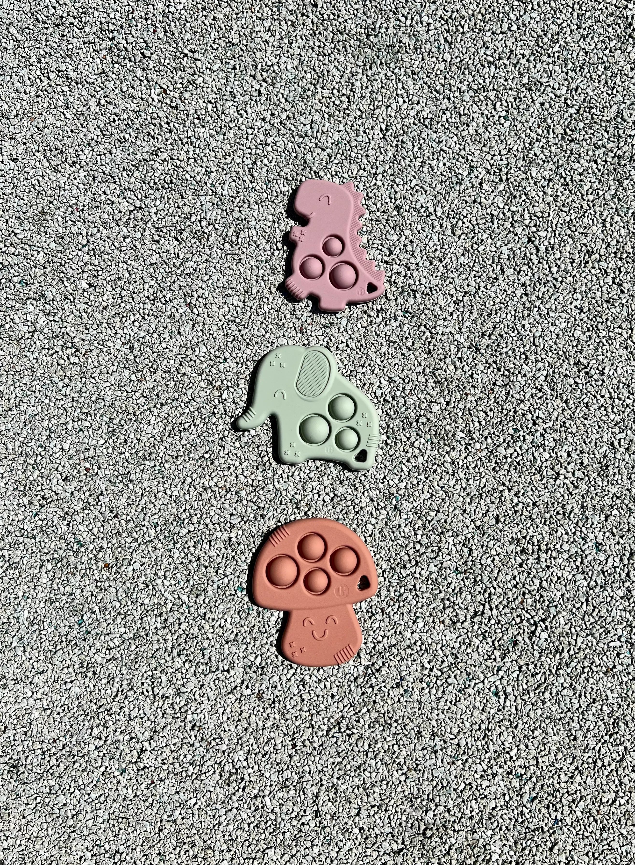Anneau de dentition Pop-It de Bim Bam Bloom sur un fond pastel, offrant un design ludique et coloré pour soulager les gencives de bébé.