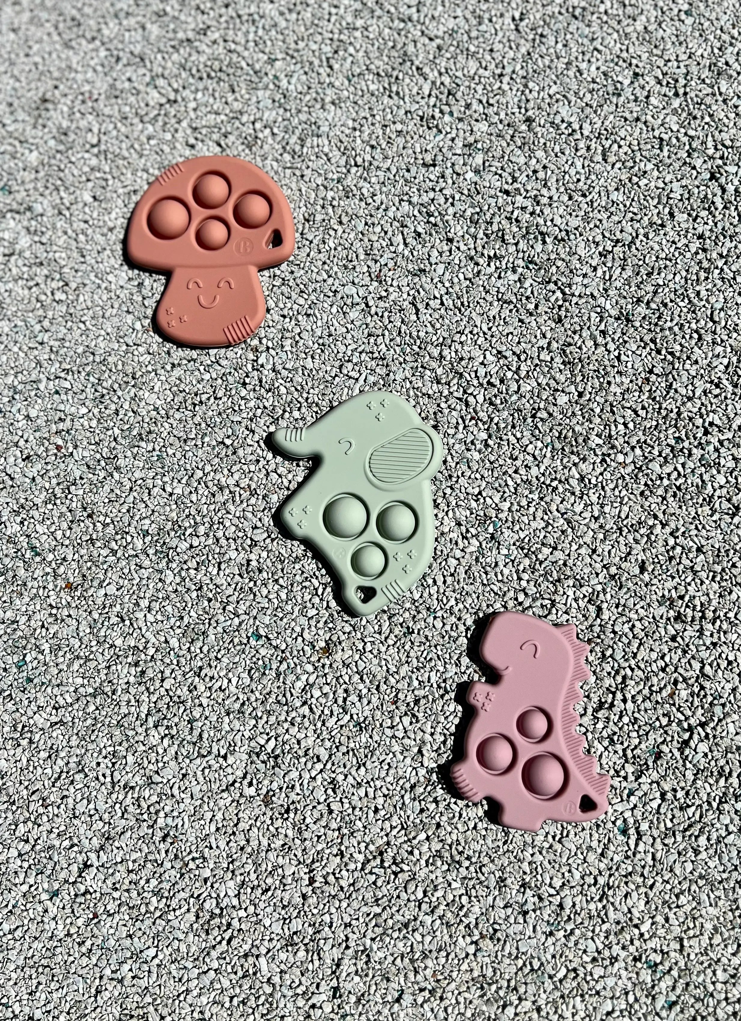 Anneau de dentition Pop-It de Bim Bam Bloom sur un fond pastel, offrant un design ludique et coloré pour soulager les gencives de bébé.