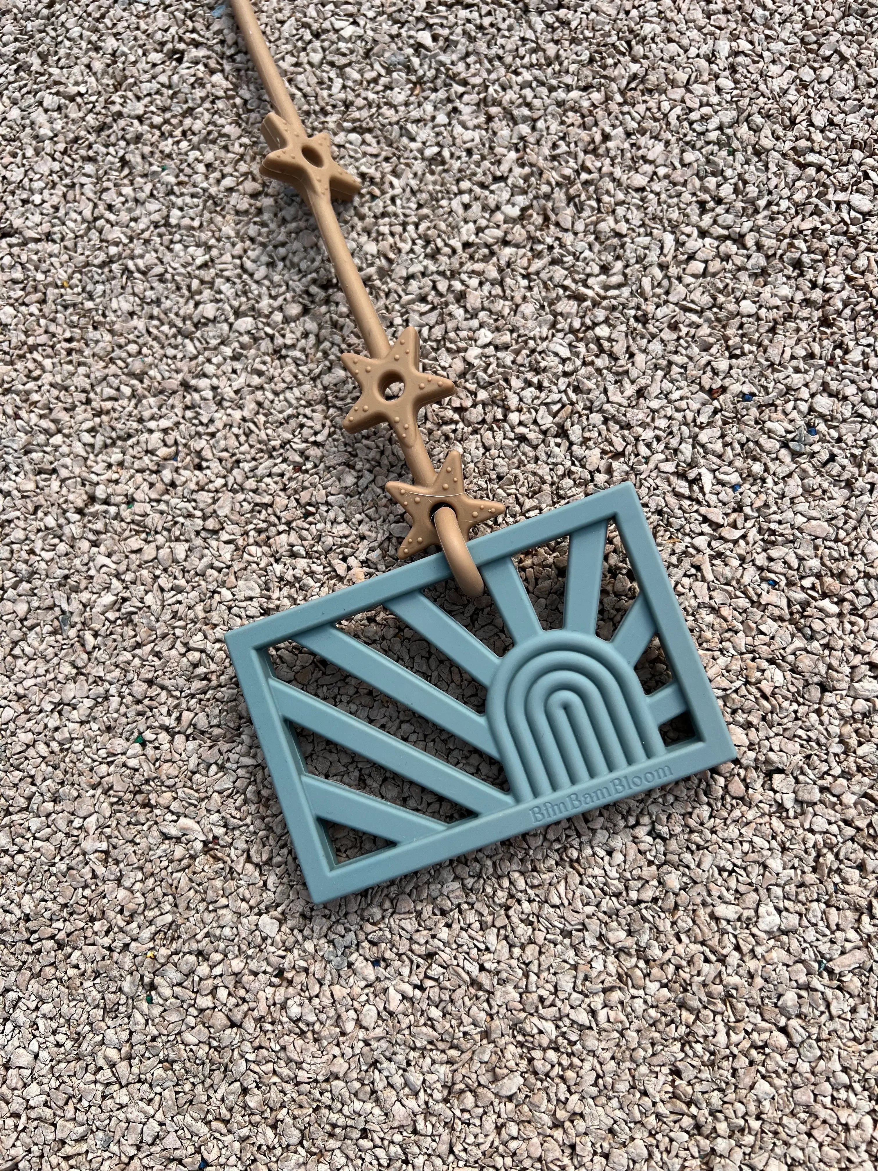 Anneau de dentition Rainbow attaché à un attache-doudou Lovie Link® pour mâchouiller en toute tranquillité, garantissant que le jouet reste toujours à portée de main, par Bim Bam Bloom