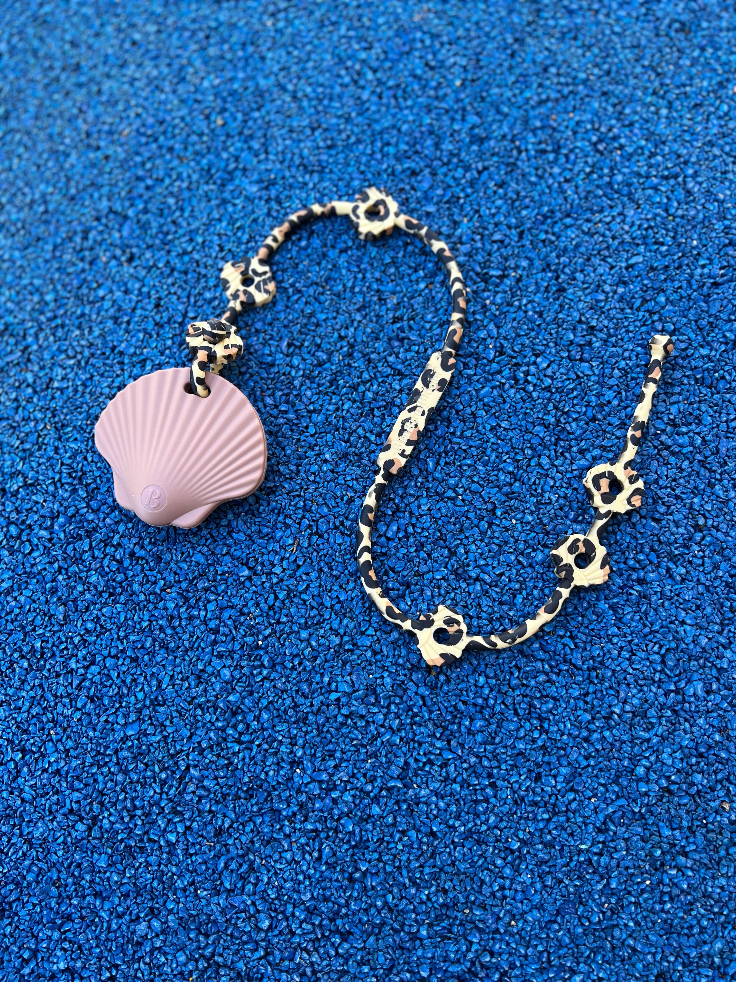 Anneau de dentition Shell Rose attaché à un attache doudou Lovie Link léopard, offrant sécurité et praticité lors des sorties par Bim Bam Bloom.