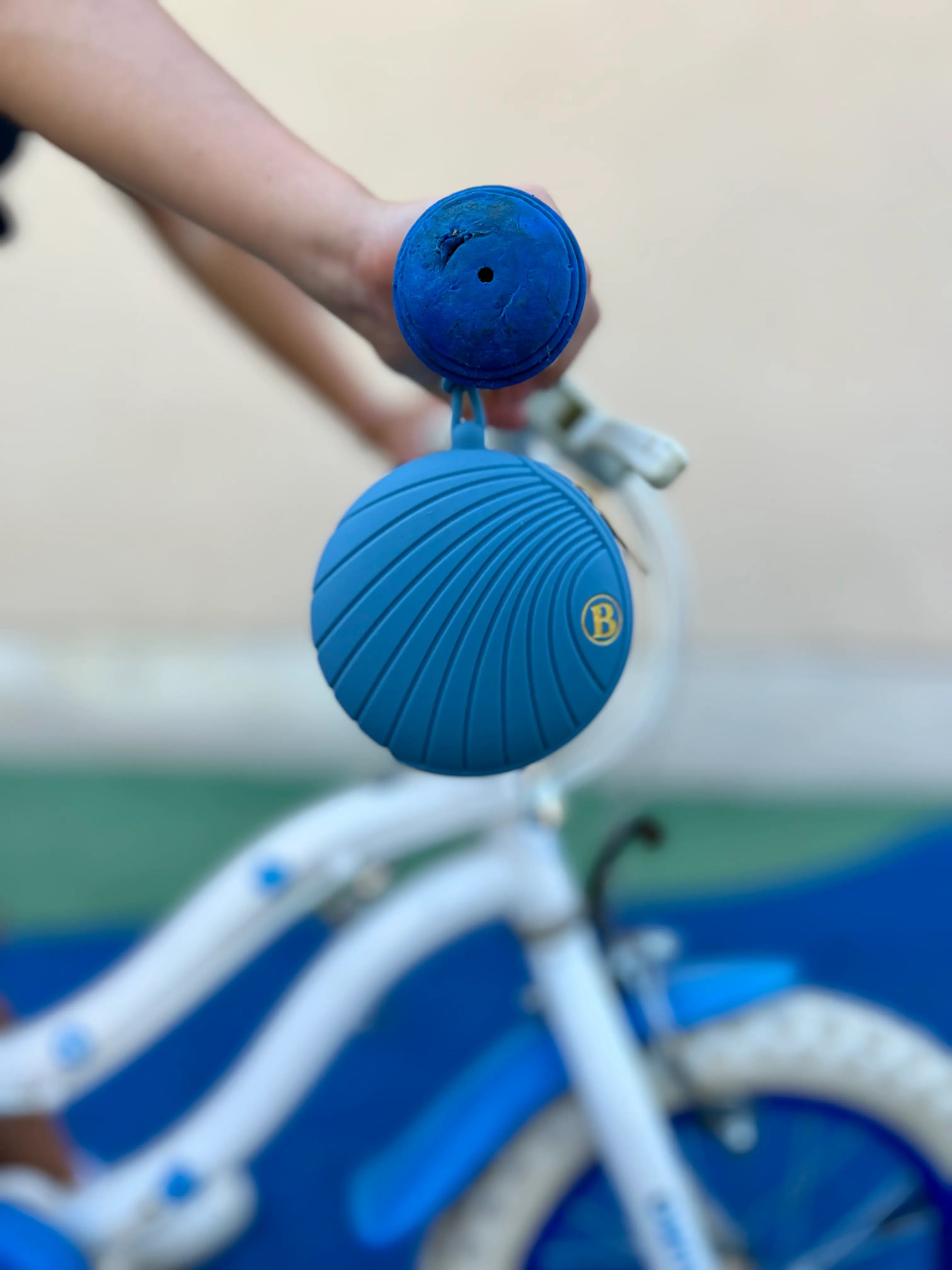 Boîte à tétines en silicone bleu Bim Bam Bloom accrochée à la poignée d'un vélo