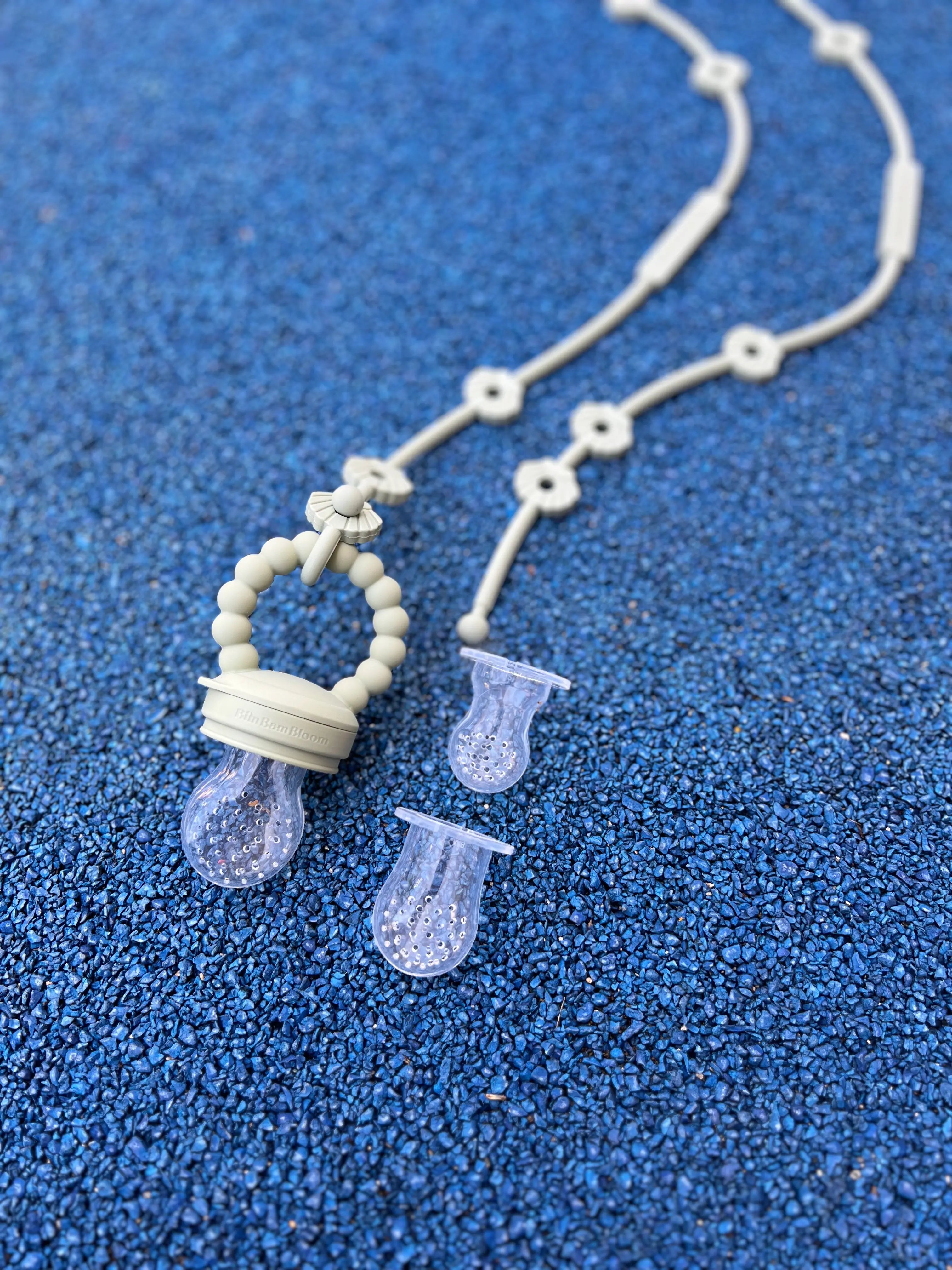 Gros plan sur Pack Tetine grignoteuse, a fruit, gourmande Yummy Tot Shell vert avec ses trois tailles de tetines et ses deux attaches Lovie Link Shell.