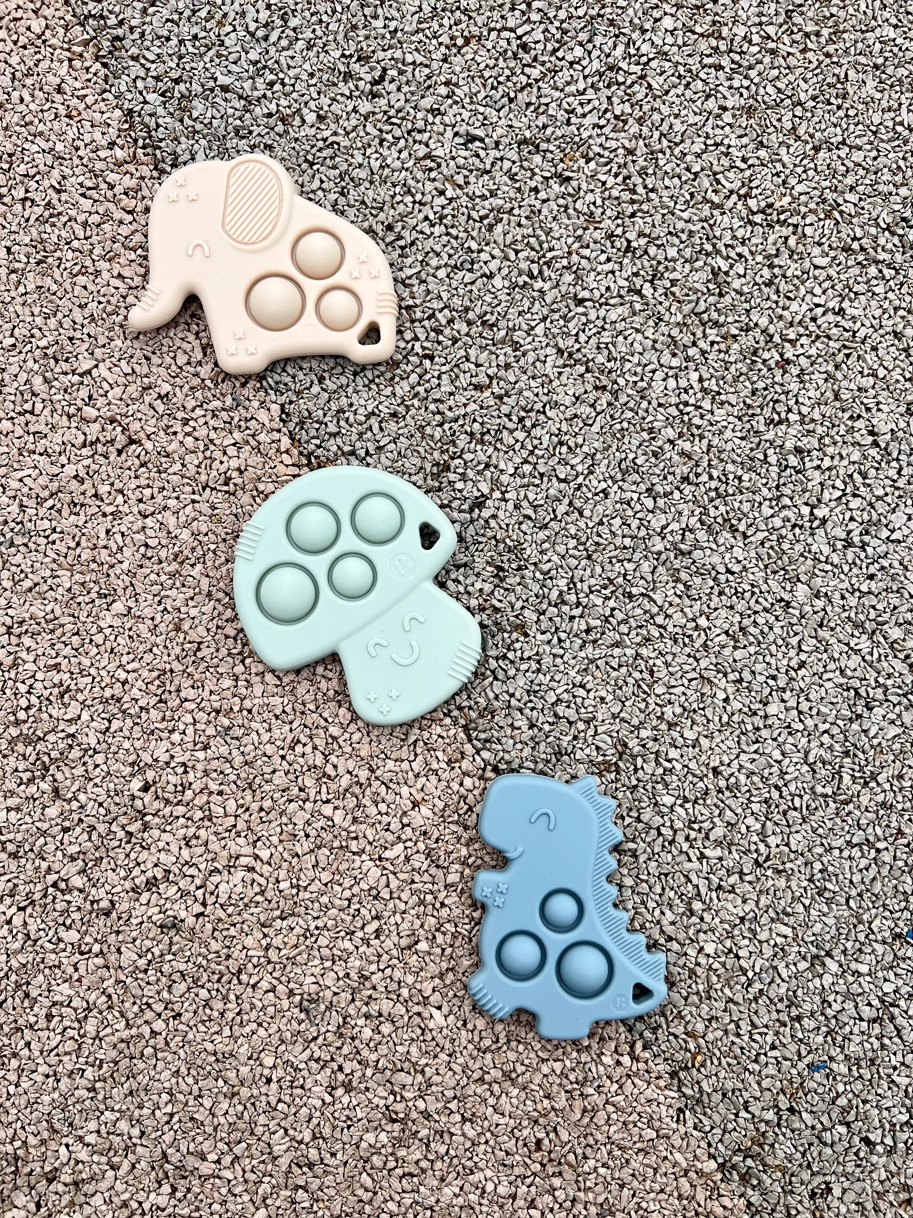 Anneaux de dentition Pop-It par Bim Bam Bloom. Soulagement des gencives douloureuses de baby. Ce trio de jouet de dentition comprenant un elephant creme, un champignon vert et un dinosaure bleu raviera votre petit.