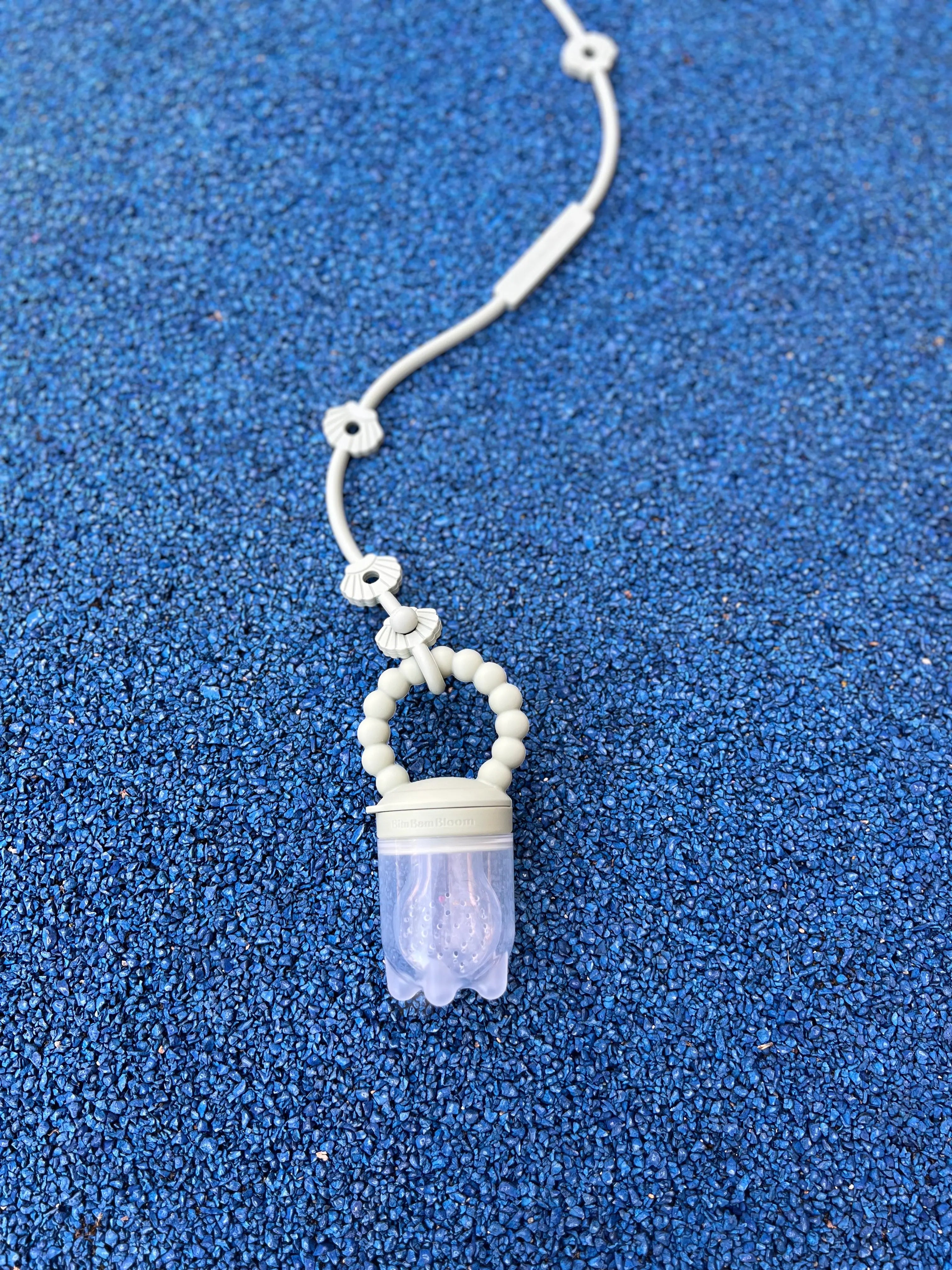 Tetine grignoteuse, gourmande Yummy Tot attachee au Lovie Link Coquillage et son capuchon de transport pour transporter votre tetine a fruit Bim Bam Bloom en toute proprete.