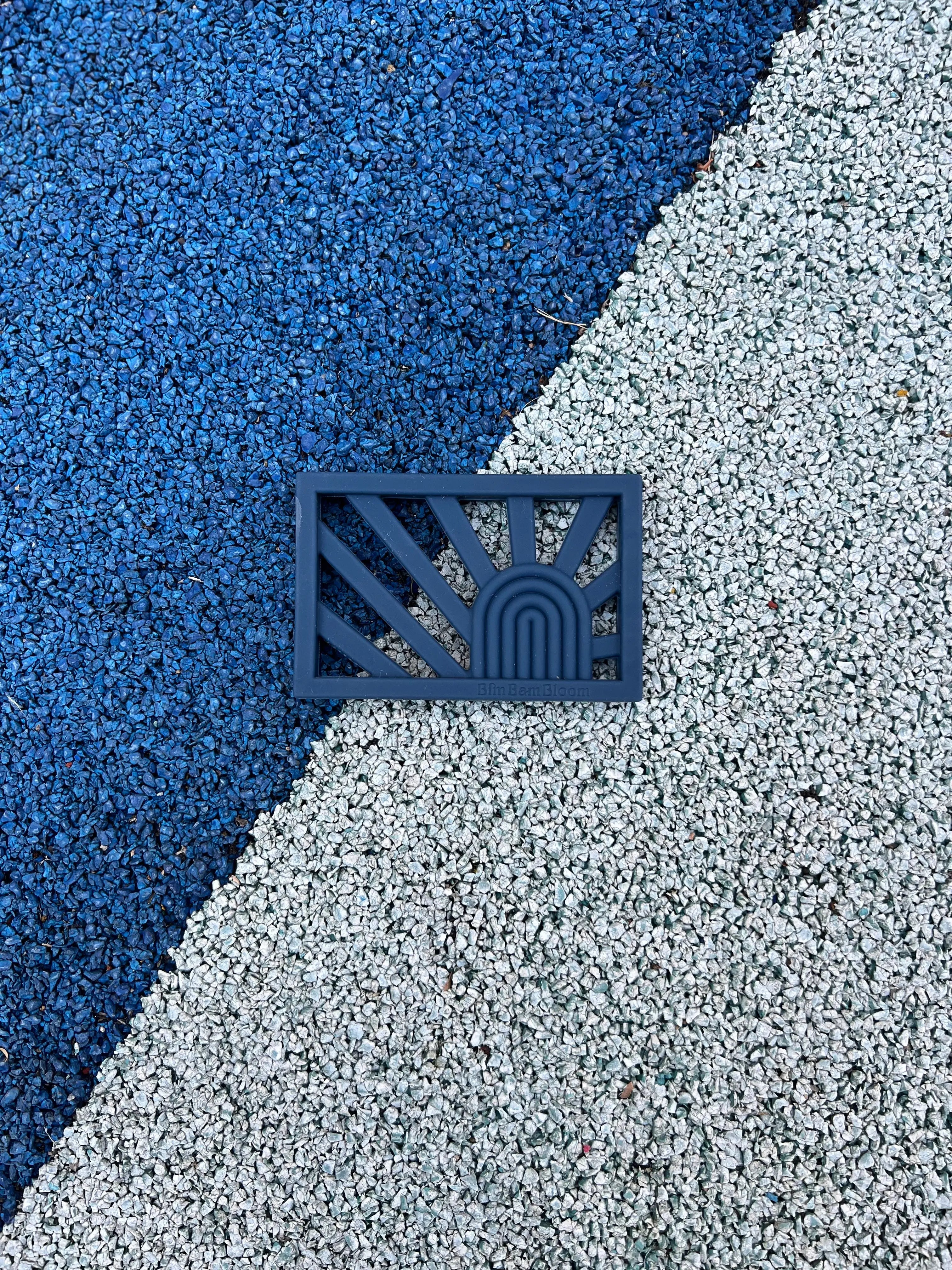 Anneau de dentition Rainbow en couleur Bleu Celeste sur un fond vibrant, un jouet de dentition sûr et sain pour apaiser les gencives de bébé par Bim Bam Bloom.