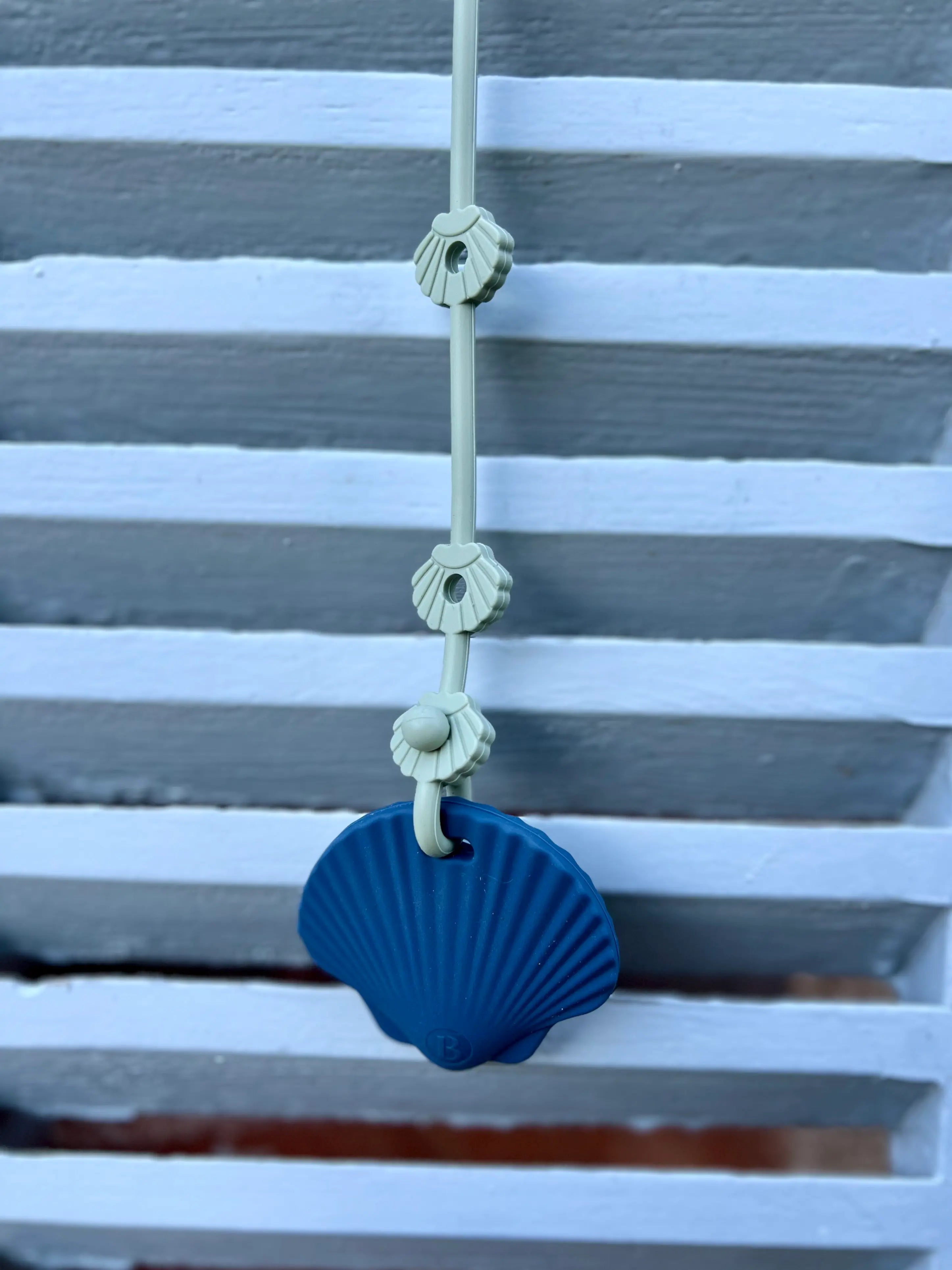 Anneau de dentition Shell au design Coquillage Bleu Celeste attaché à une laisse pour doudou Lovie Link, offrant sécurité et praticité lors des sorties.