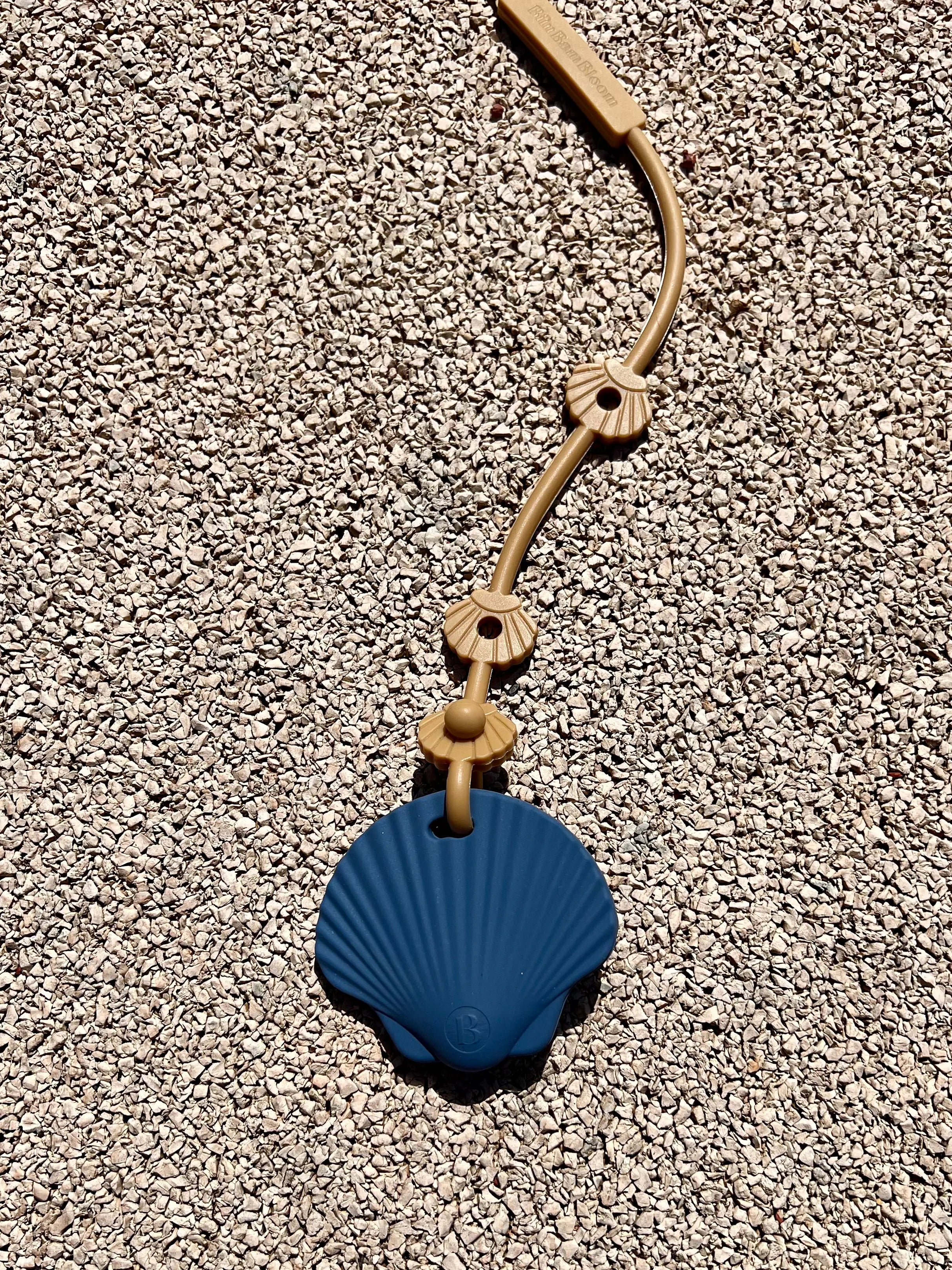 Laisse à doudou Lovie Link® Shell camel dune dorée en silicone sans BPA, ni phtalates avec notre anneau de dentition shell bleu Bim Bam Bloom, pour des sorties sereines et organisées.