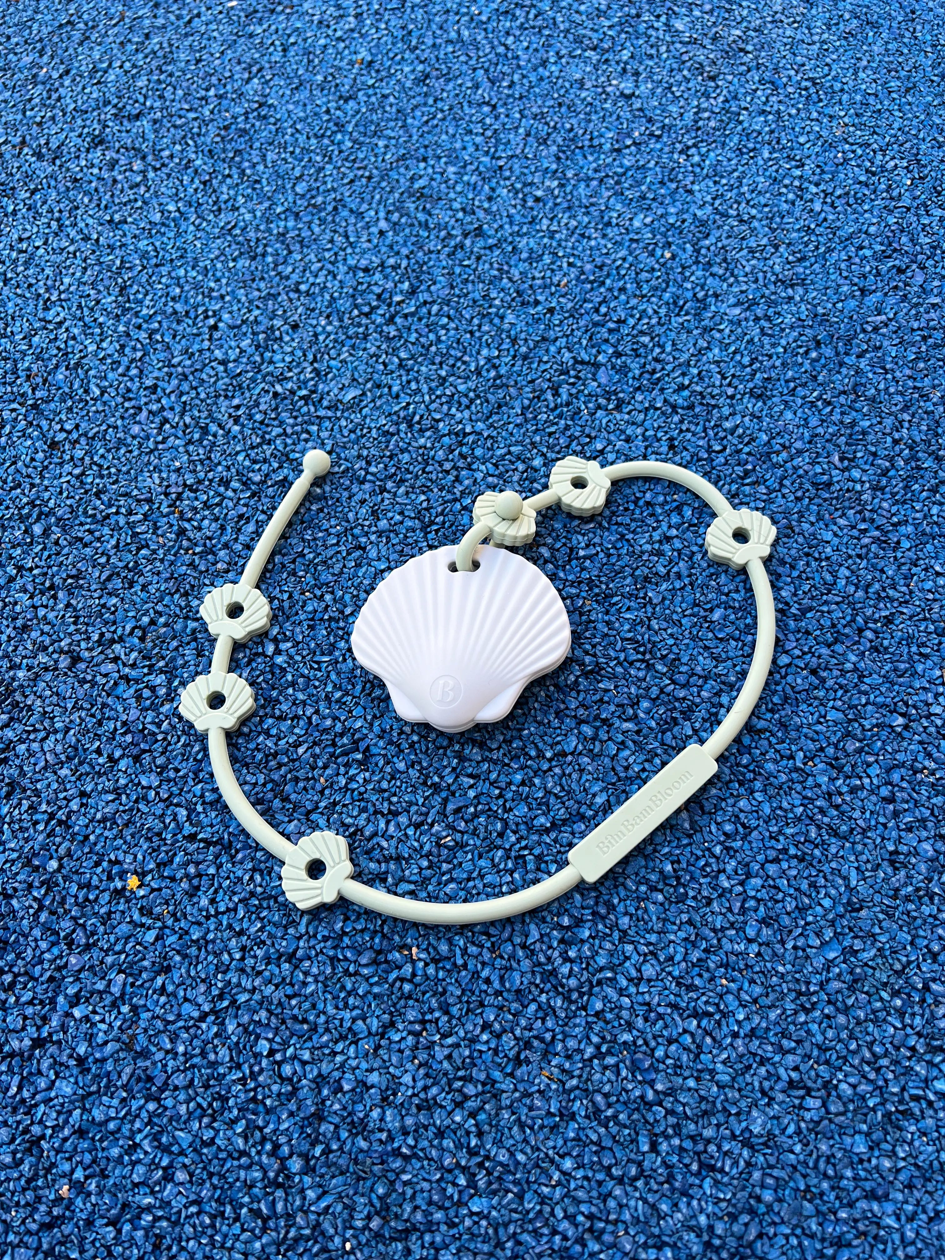 Attache doudou Lovie Link® Shell Vert Crème Glacée Pistache attaché à un anneau de dentition Shell Bim Bam Bloom, combinant sécurité et praticité pour bébé. Attachez le facilement à la poussette.