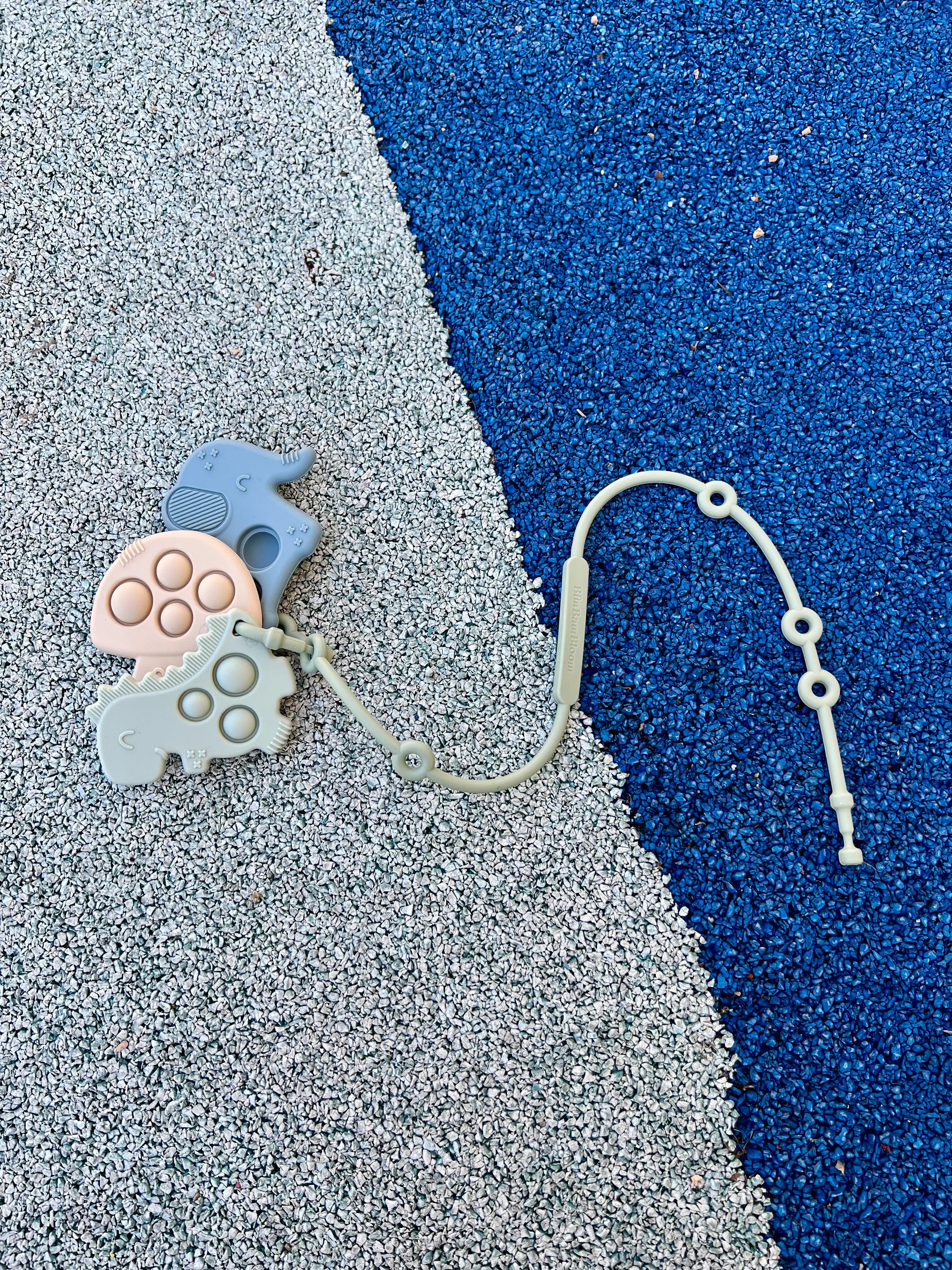 Attache doudou et anneau de dentition Lovie Link par Bim Bam Bloom vert en silicone sans BPA. La solution pour ne plus jamais perdre doudou. Se fixe facilement à la poussette de votre bébé.