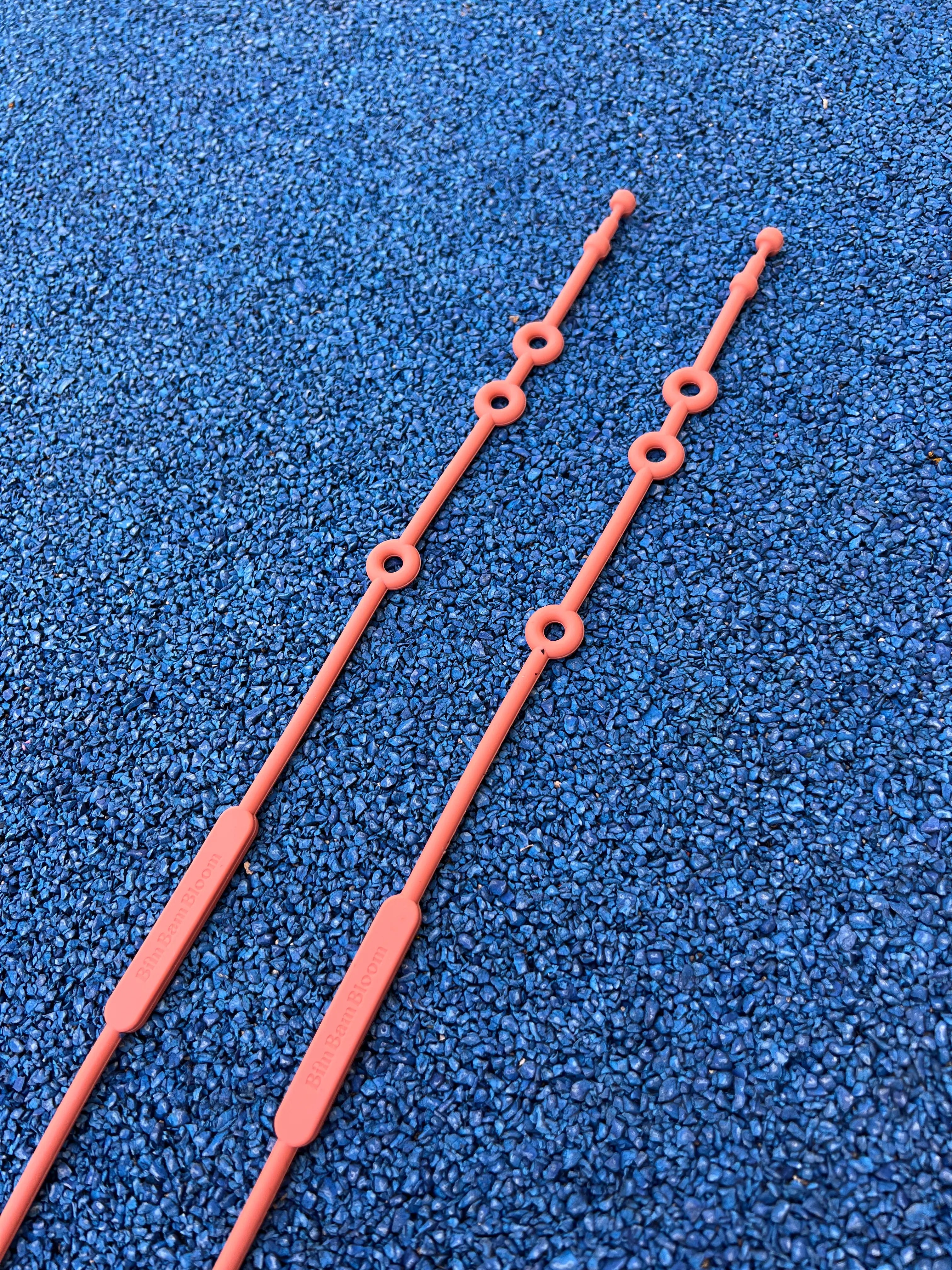 Gros plan sur les trois tailles de fixation de nos attaches doudou pour poussette Lovie Link Terracotta Bim Bam Bloom en silicone sans BPA ni Phtalates qui se fixe facilement à la poussette de votre bébé. C'est la solution pour ne plus perdre doudou.