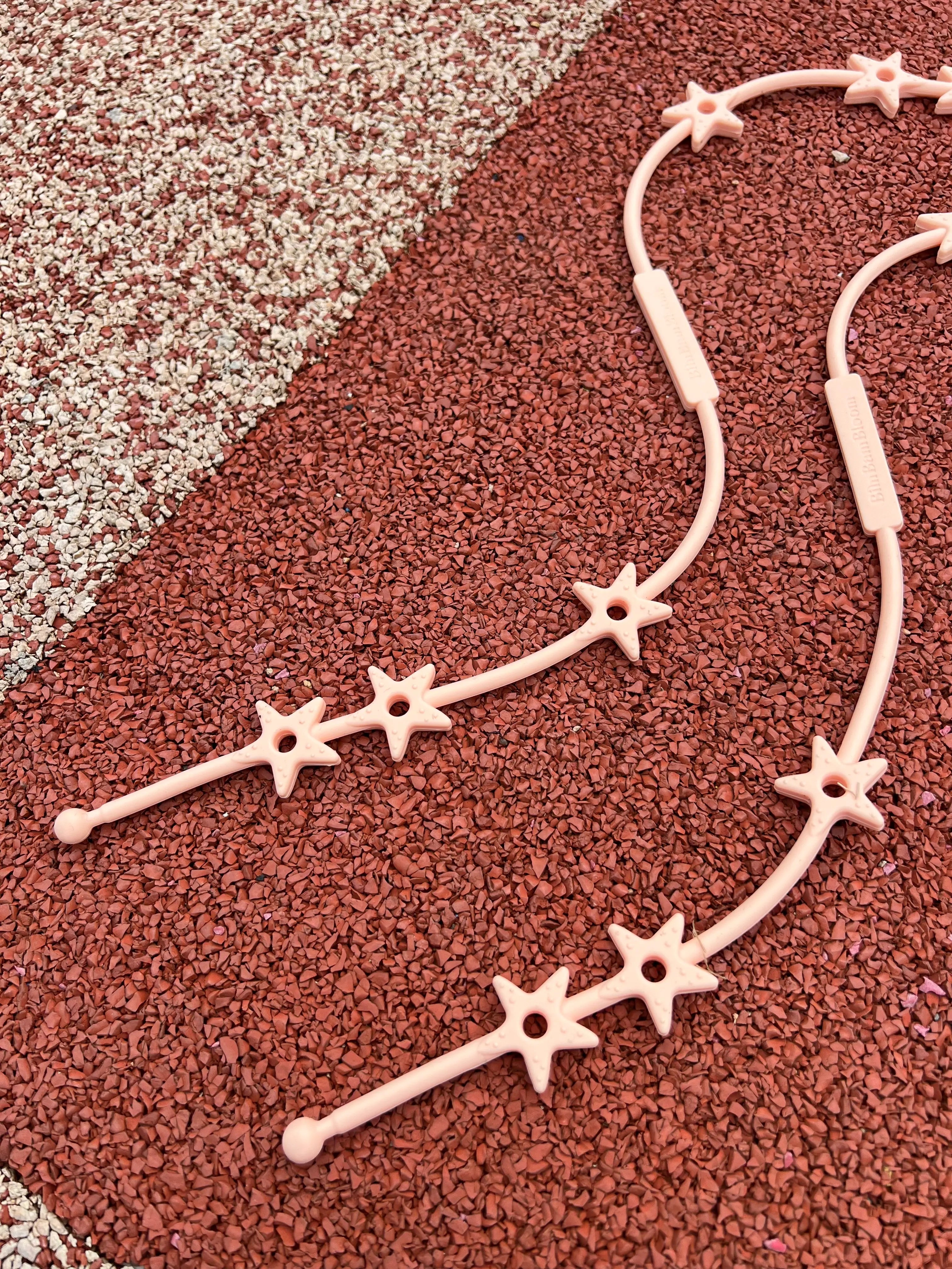 Gros plan sur les étoiles de nos attaches doudous pour poussette Lovie Link® Star en rose guimauve fondante, un accessoire essentiel pour garder le doudou de bébé toujours à portée de main par Bim Bam Bloom.