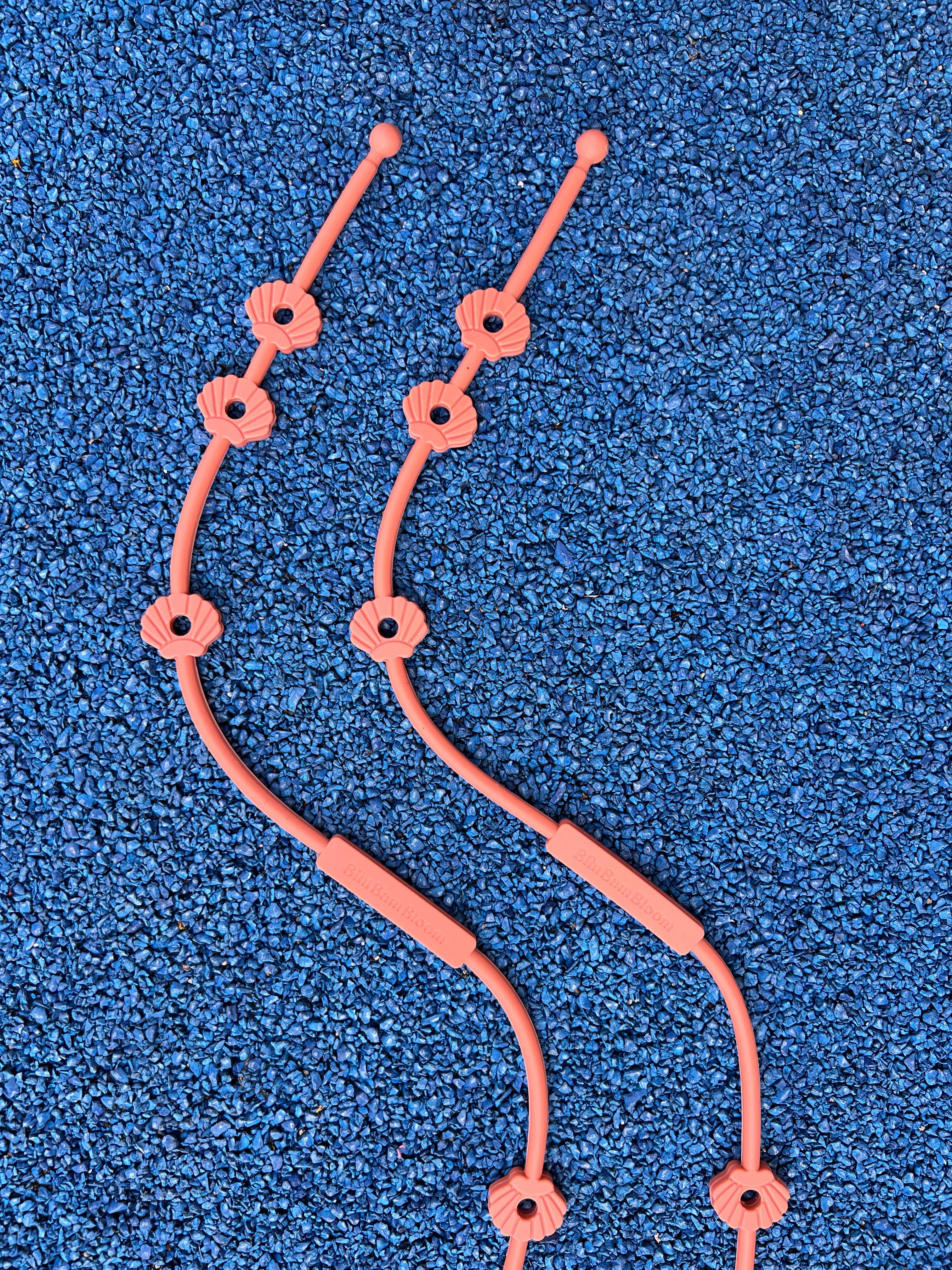 Deux Lovie Link® Shell en terracotta coucher de soleil, un accessoire indispensable pour garder le doudou de bébé toujours en securité par Bim Bam Bloom.