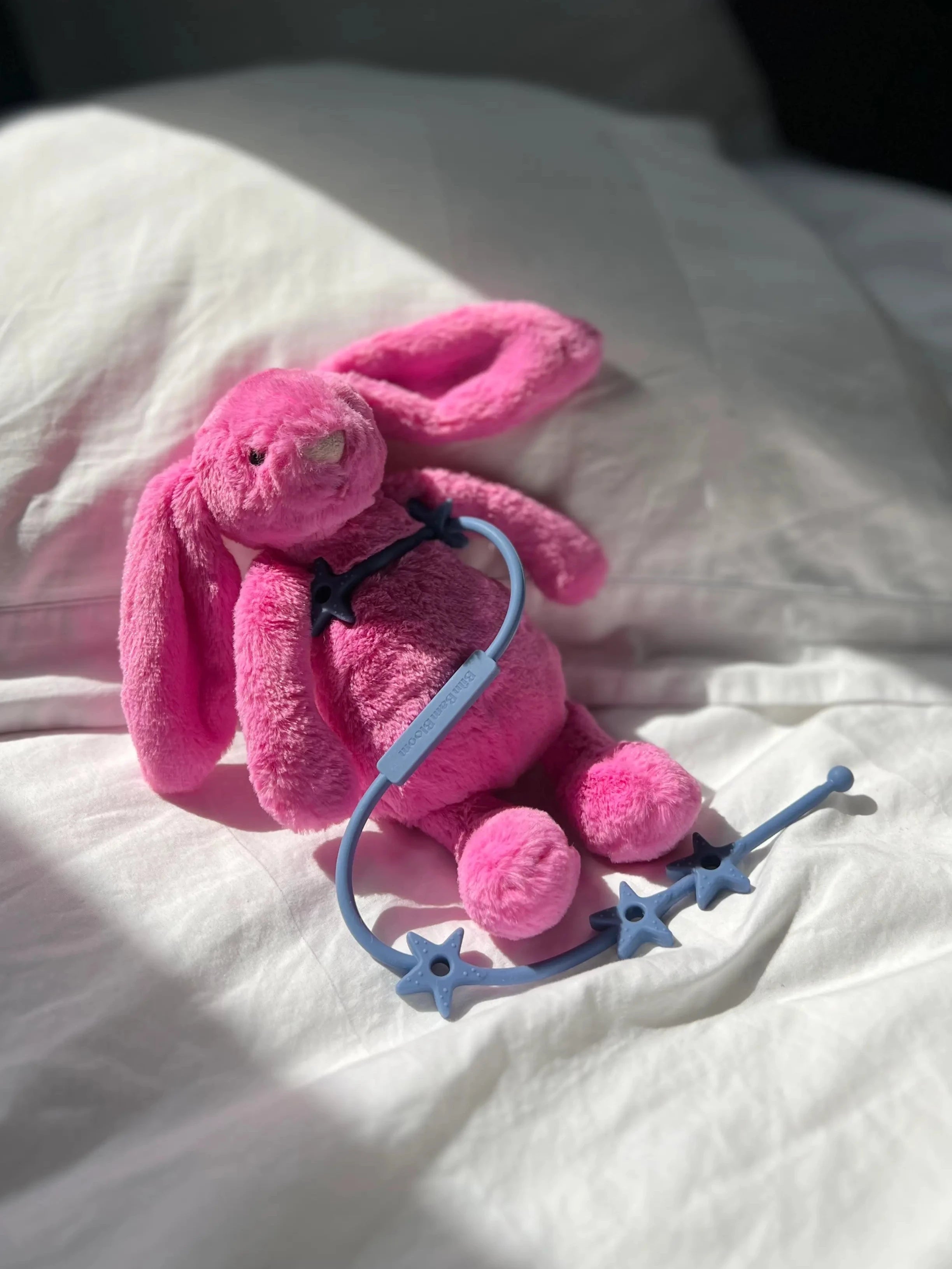 Attache doudou Lovie Link® Star en bleu reve de farniente attaché à un doudou lapin rose. Le doudou de bébé est toujours à portée de main et en securité. Fini les doudous perdus !