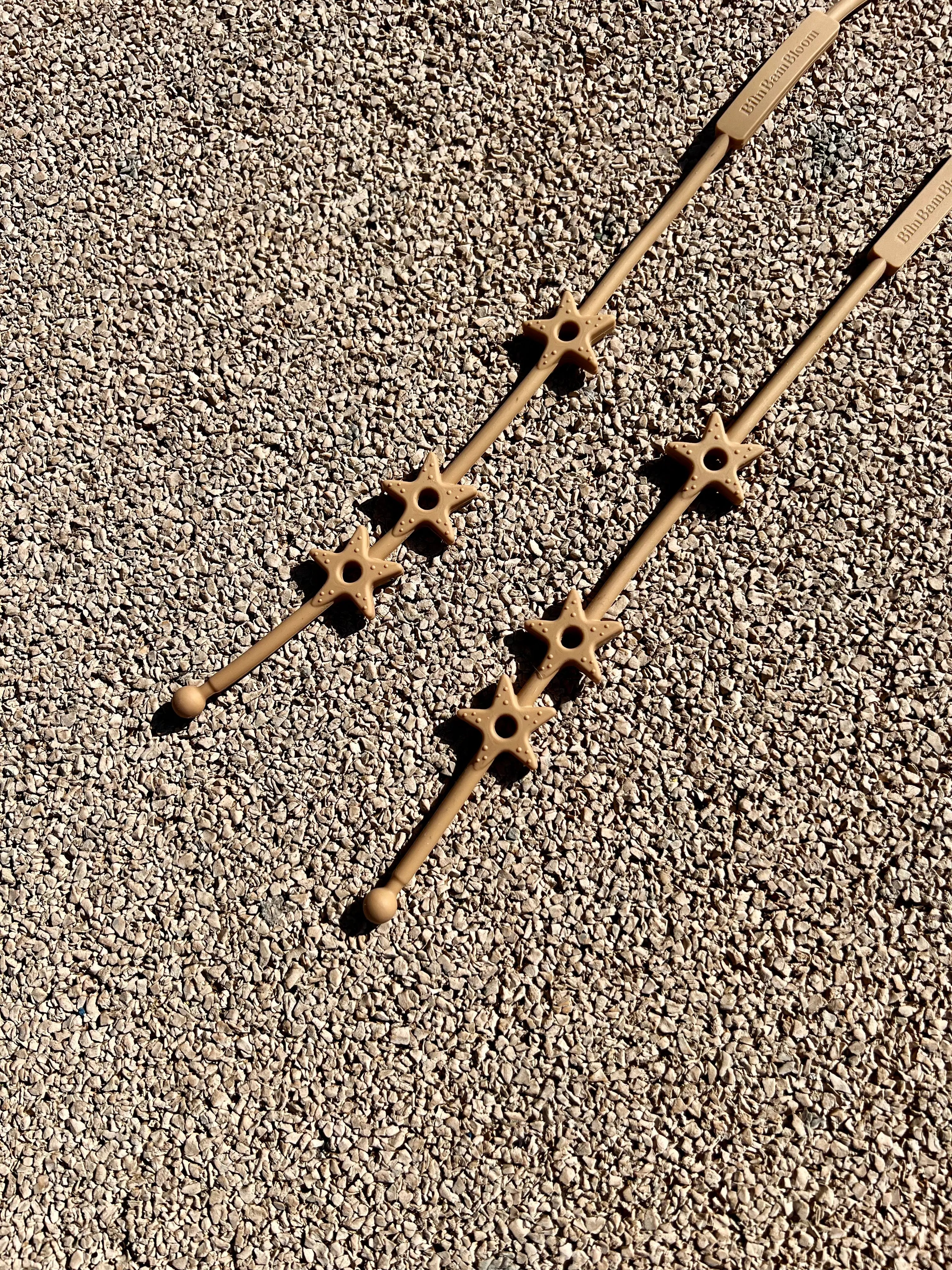 Gros plan sur les étoiles texturées de nos laisses à doudou Lovie Link® Star Bim Bam Bloom en camel, un accessoire indispensable pour garder le doudou de bébé toujours à portée de main. Fini les doudous perdus.