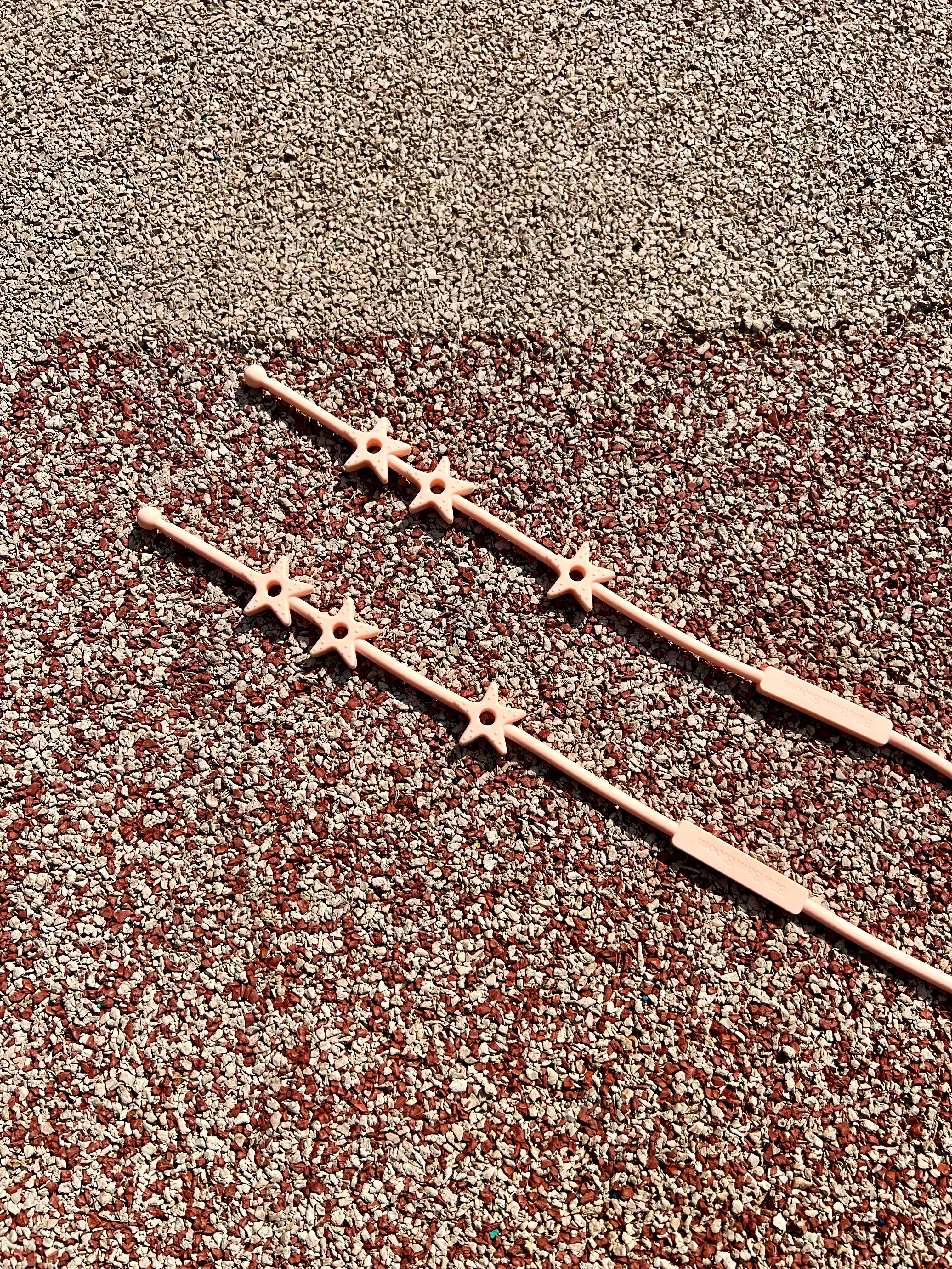 Gros plan sur les etoiles de notre laisse pour doudou Lovie Link® Star rose guimauve fondante sur un fond pastel, mettant en avant son design adorable et tendance.