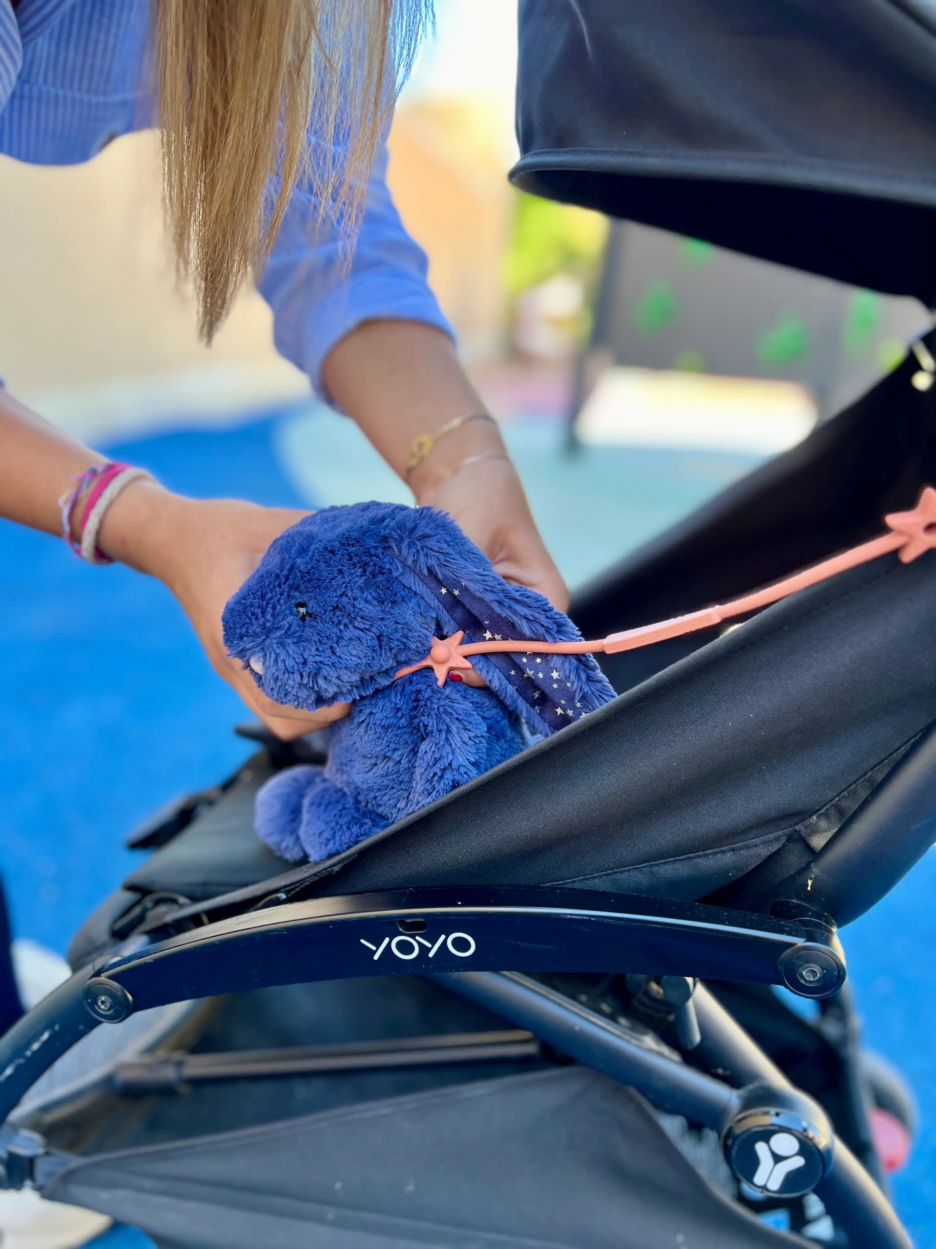 Laisse à doudou Lovie Link® Terracotta fixée à une poussette et à un doudou lapin, garantissant des sorties sereines et organisées pour les parents. Fini les doudous perdus avec Bim Bam Bloom!