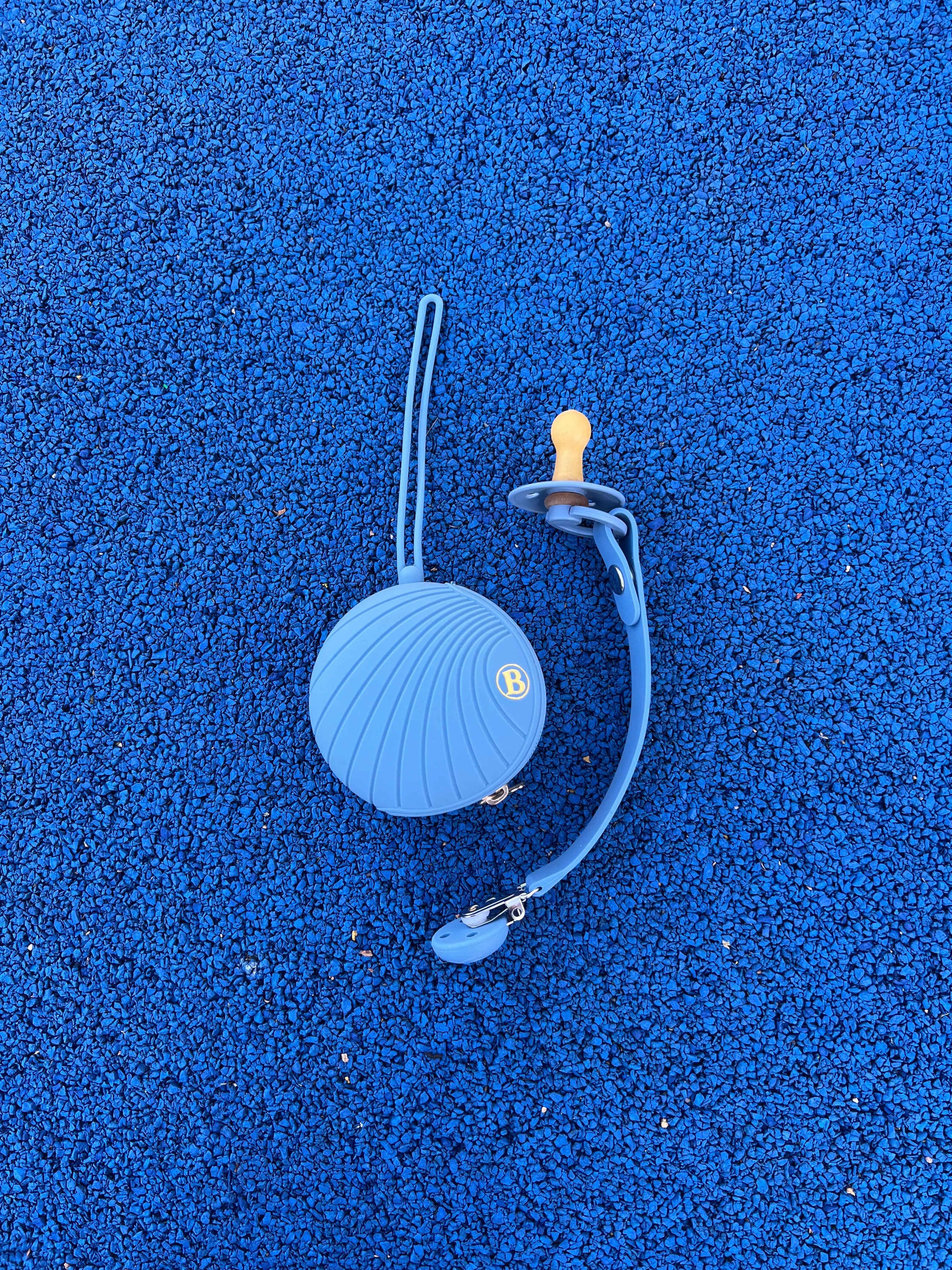 Attache tétine en silicone bleu sans BPA ni phtalates Bim Bam Bloom a coté de la boite a tétine en silicone Bleu Bim Bam Bloom, pour fille et garcon.