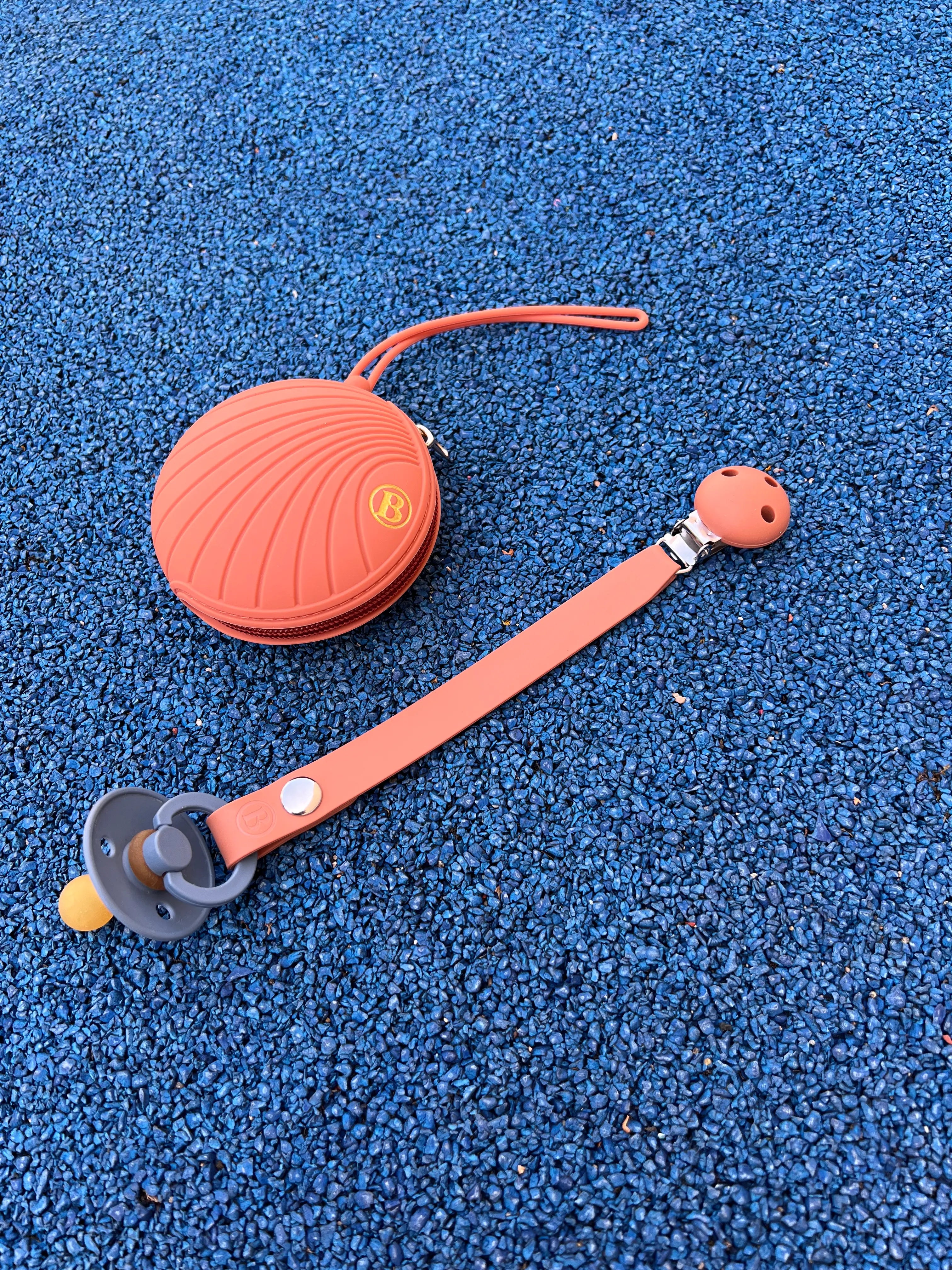 Attache tetine en silicone terracotta Bim Bam Bloom avec une boite a tetine en silicone terracotta.