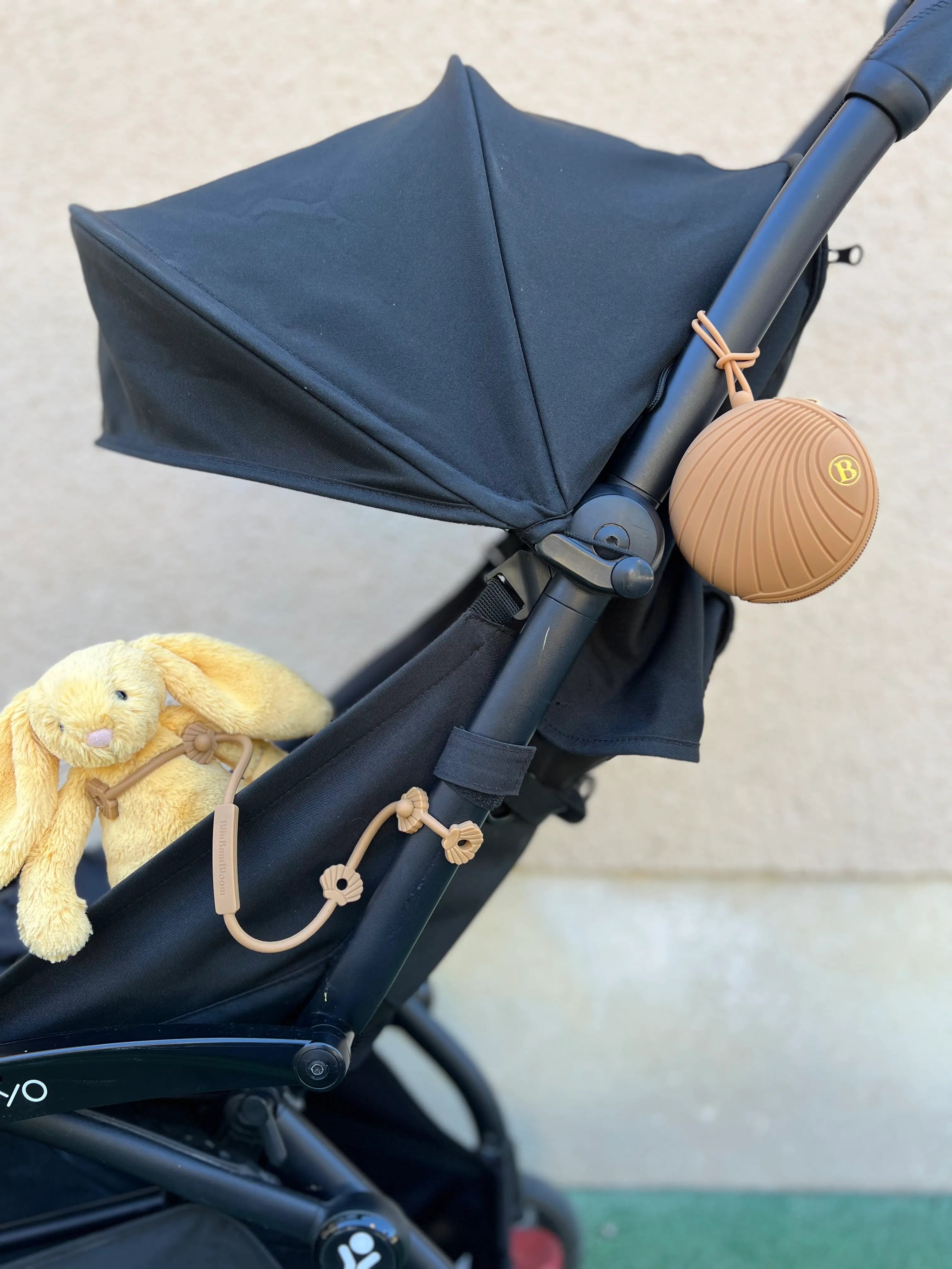 Boîte à Tétines camel Bim Bam Bloom attache à la poussette avec un attache doudou pour poussette shell camel Lovie Link attaché à la poussette.