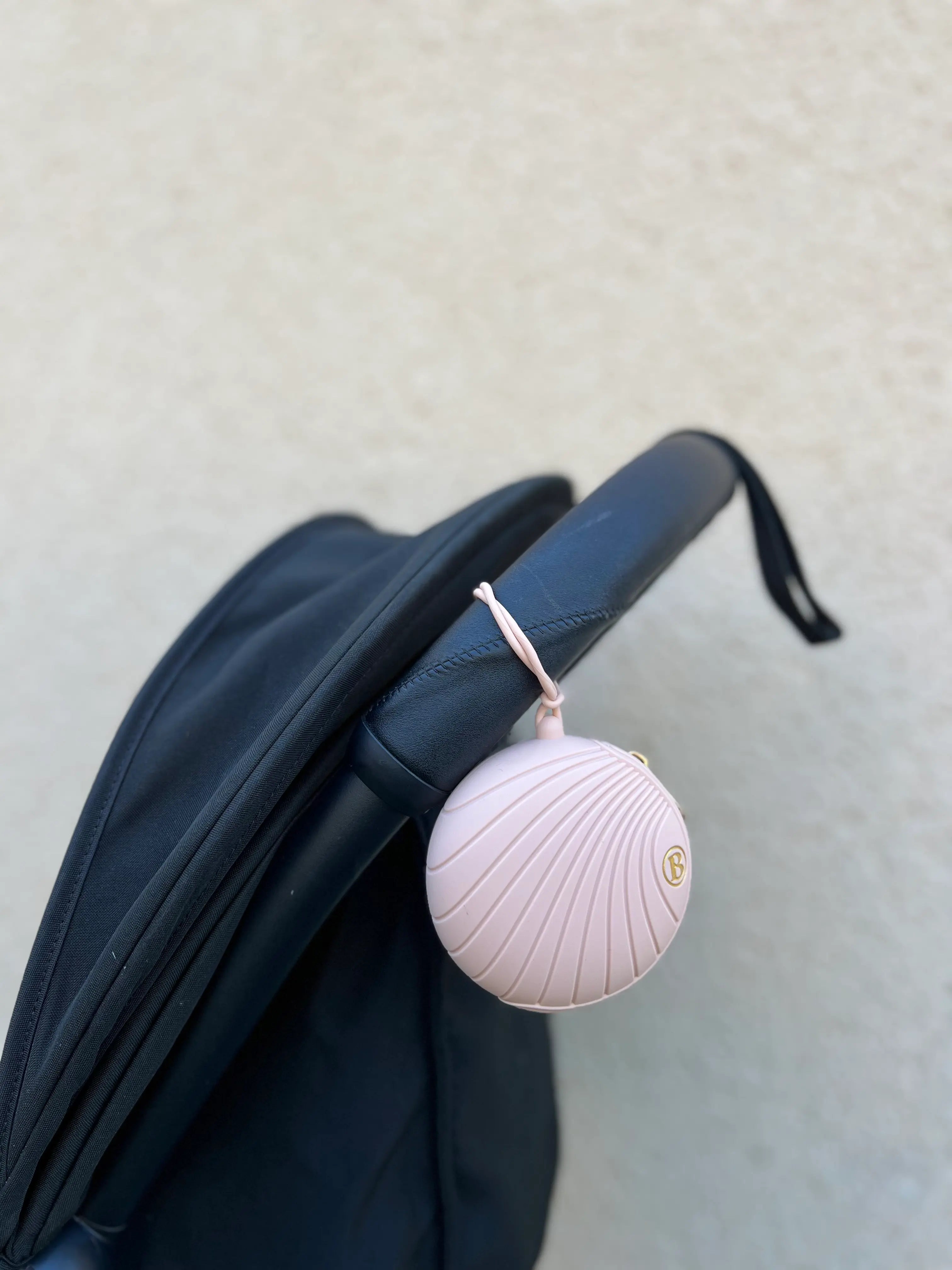 Boite a tetine rose en silicone Bim Bam Bloom attachee a une poussette. Accessoire pour bebe indispensable.