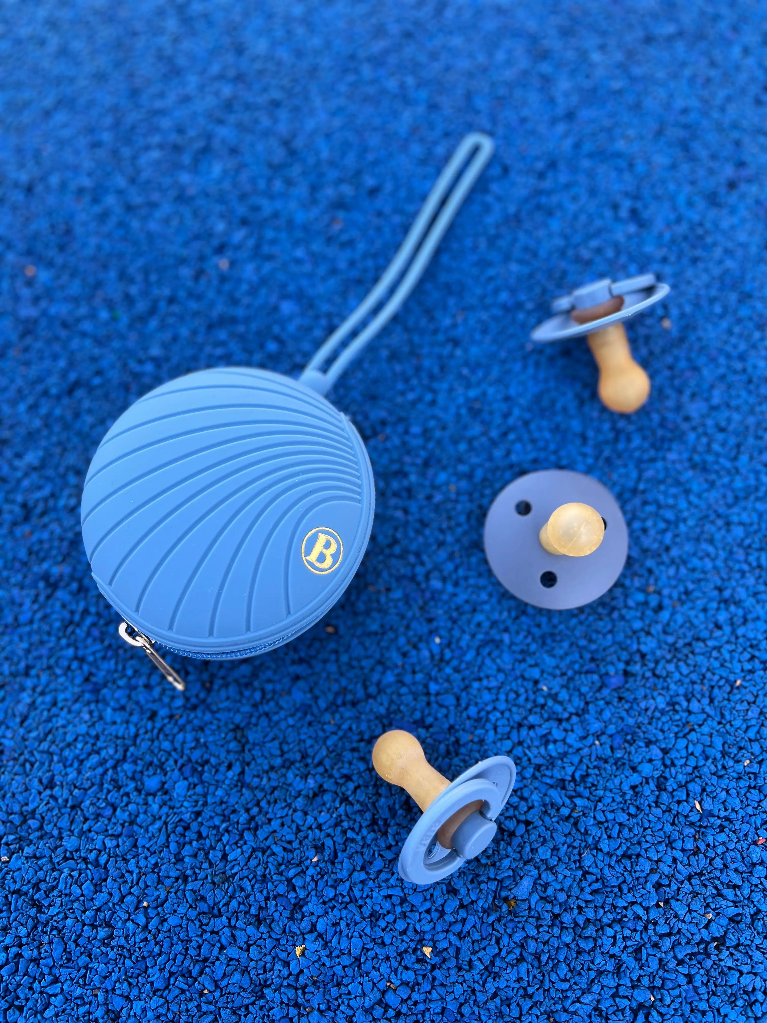 boite a tetine Bim Bam Bloom en silicone bleu avec logo dore. Peut contenir jusq'a 4 tetines