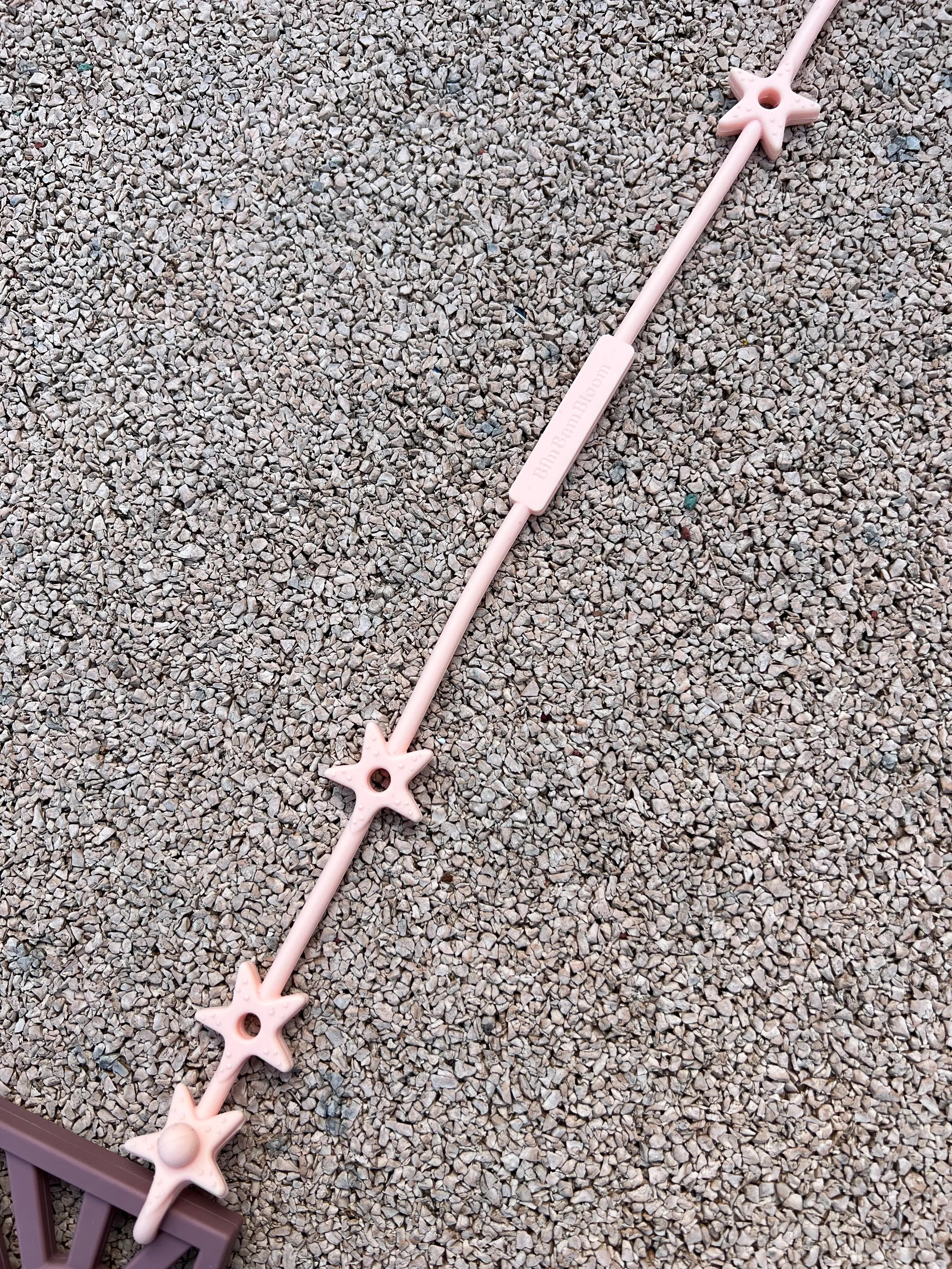 Attache anneau de dentition Lovie Link® Star en Rose Guimauve Fondante, des attaches doudou pour poussette qui assurent que le doudou de bébé reste en sécurité et à portée de main. Design étoilé texturé stimulant les sens de bébé.