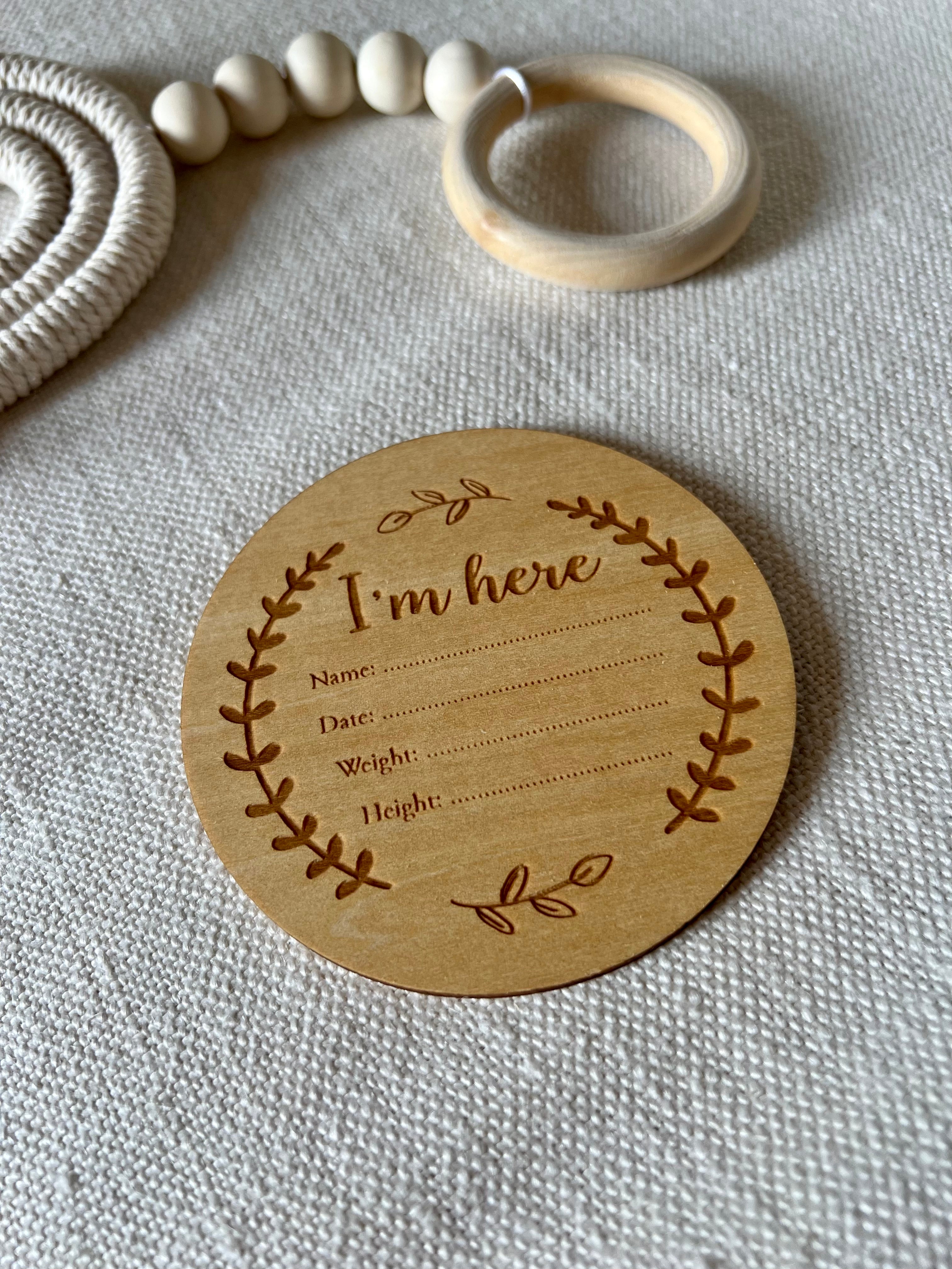 Carte naissance bébé I Am Here en bois sur fond clair pour annoncer la naissance avec douceur