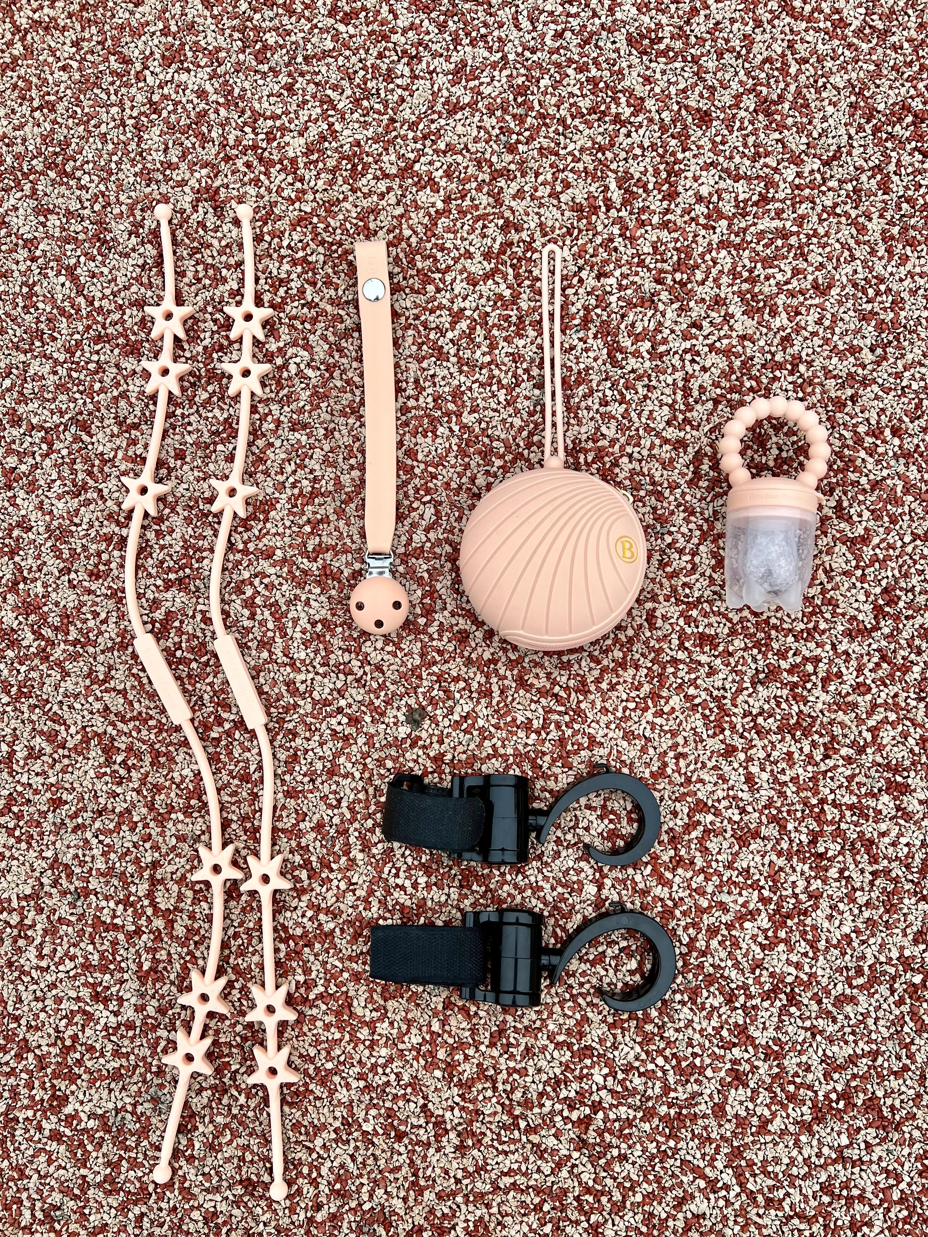 Cadeau de naissance pour bébé fille au design d'étoiles en rose. Notre coffret cadeau de naissance comprend une boîte à tétine, un attache-tétine, une tétine gourmande, deux crochets pour poussette et deux Lovie Link Star étoiles Bim Bam Bloom.