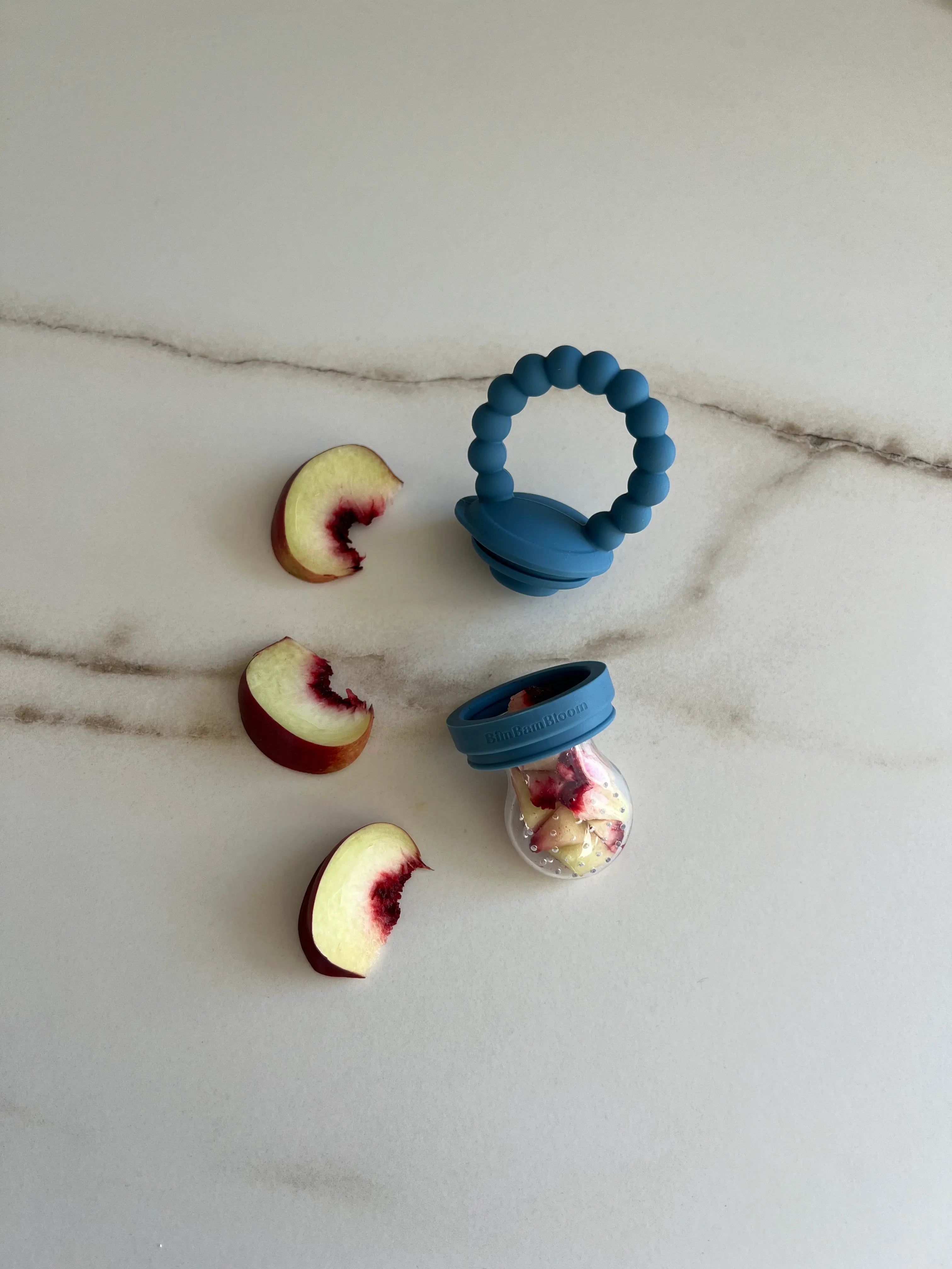 Tetine grignoteuse en silicone Bleu Bim Bam Bloom. Morceaux de nectarines dans la tetine gourmande Yummy Tot.