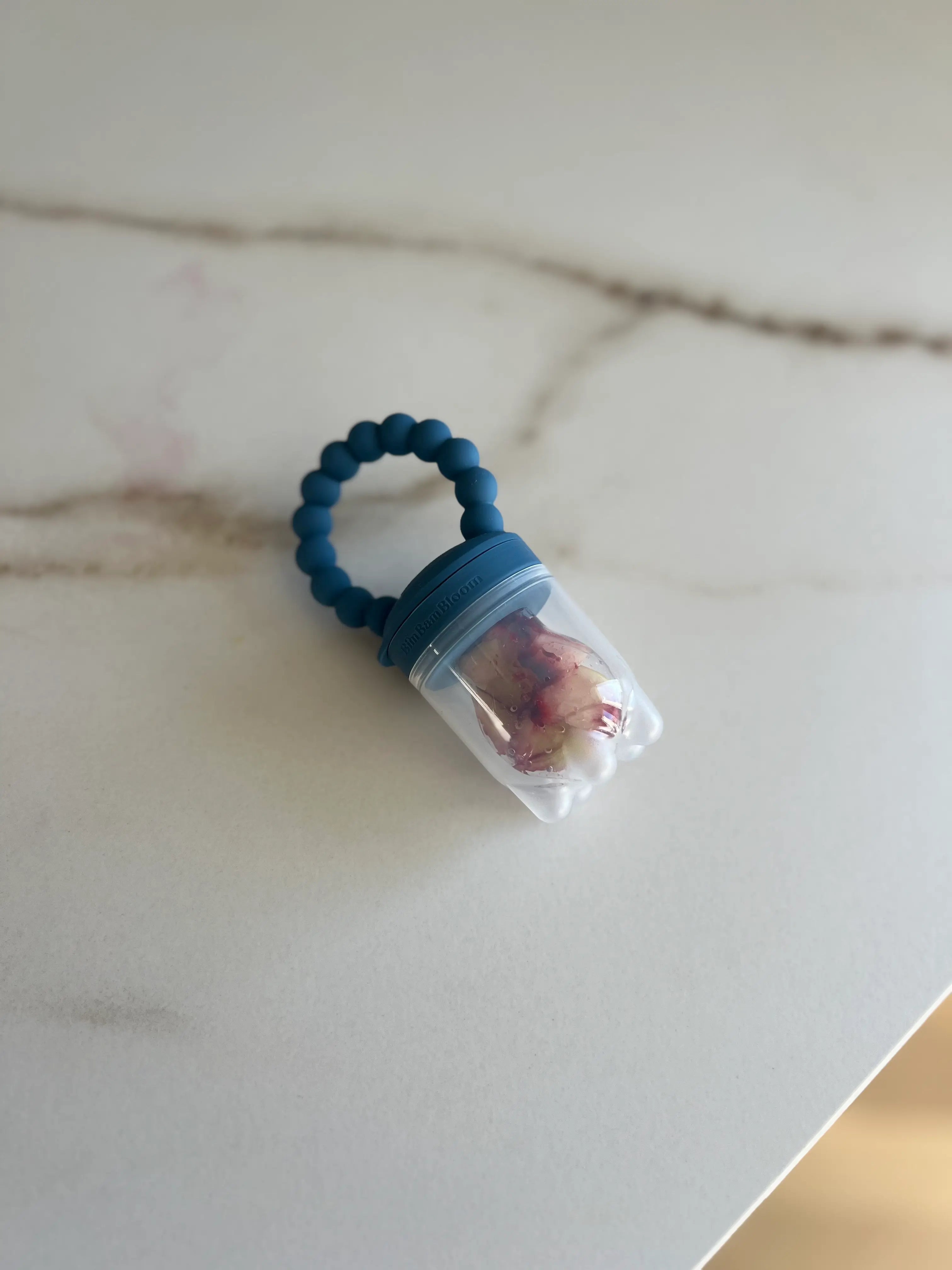 Tetine grignoteuse en silicone Bleu Bim Bam Bloom avec son capuchon protecteur.