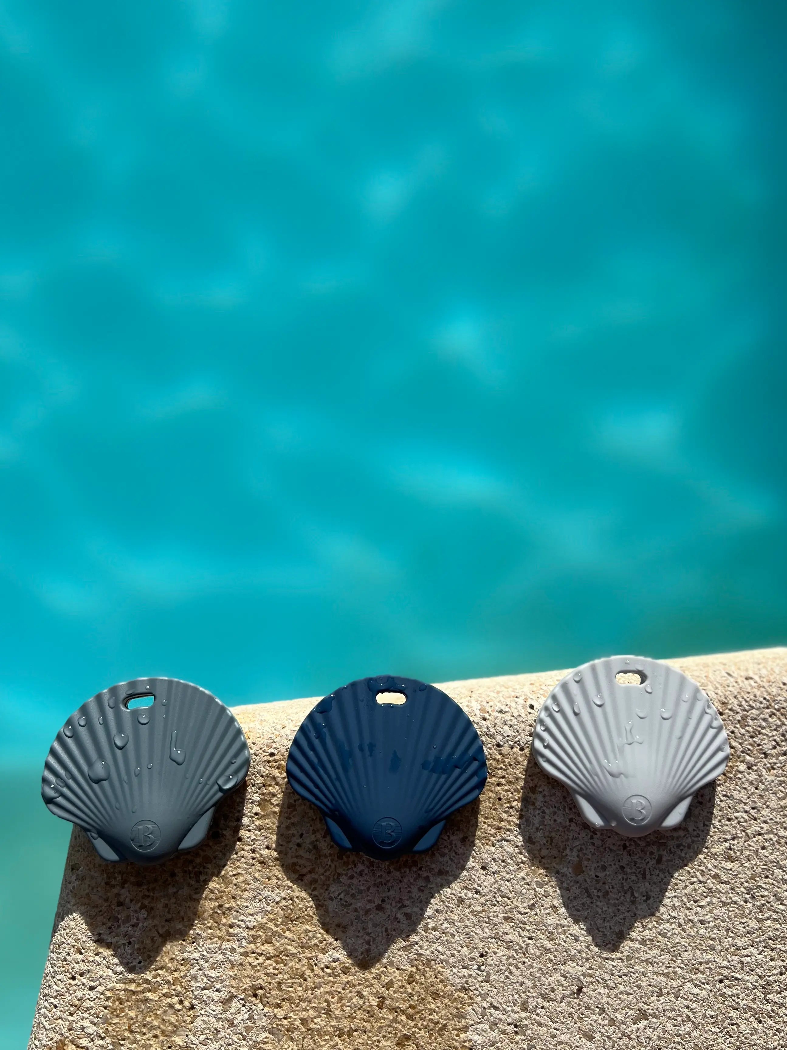 3 Anneaux de dentitions Shell Bleu Ciel, Bleu celeste et gris souris au bord de la piscine, mettant en avant le design adorable et ludique de coquillage, par Bim bam Bloom.